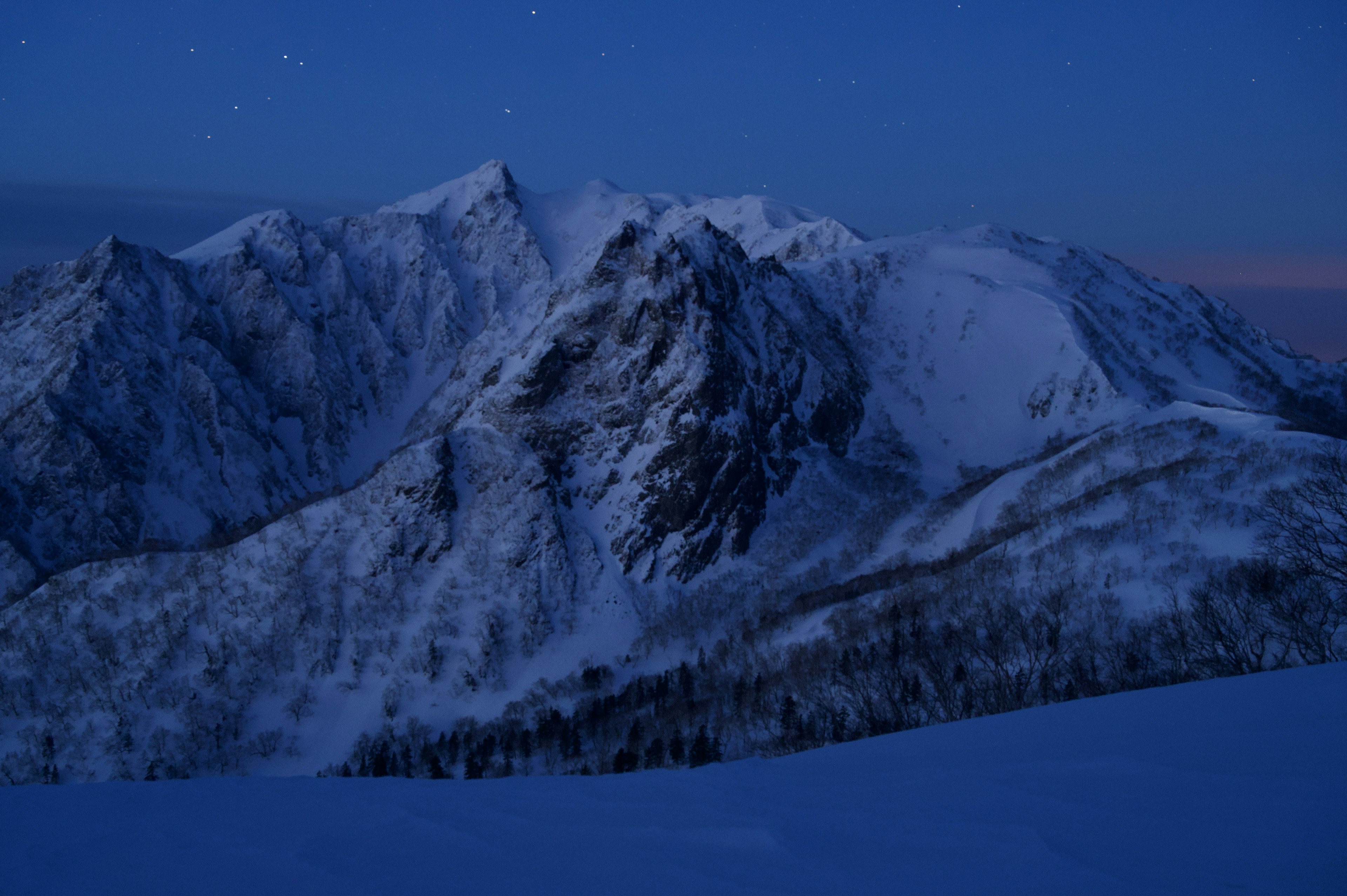 夜の雪山の美しい風景　青い空と雪に覆われた山々