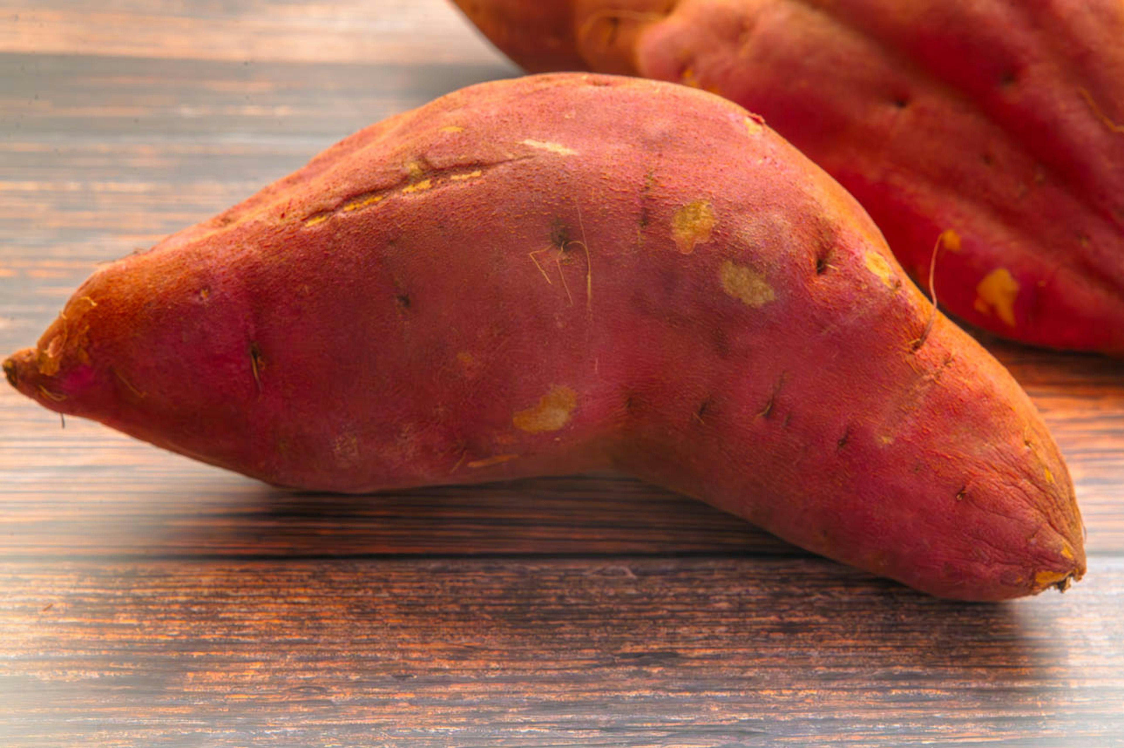 Rote-lila Süßkartoffel auf einem Holztisch