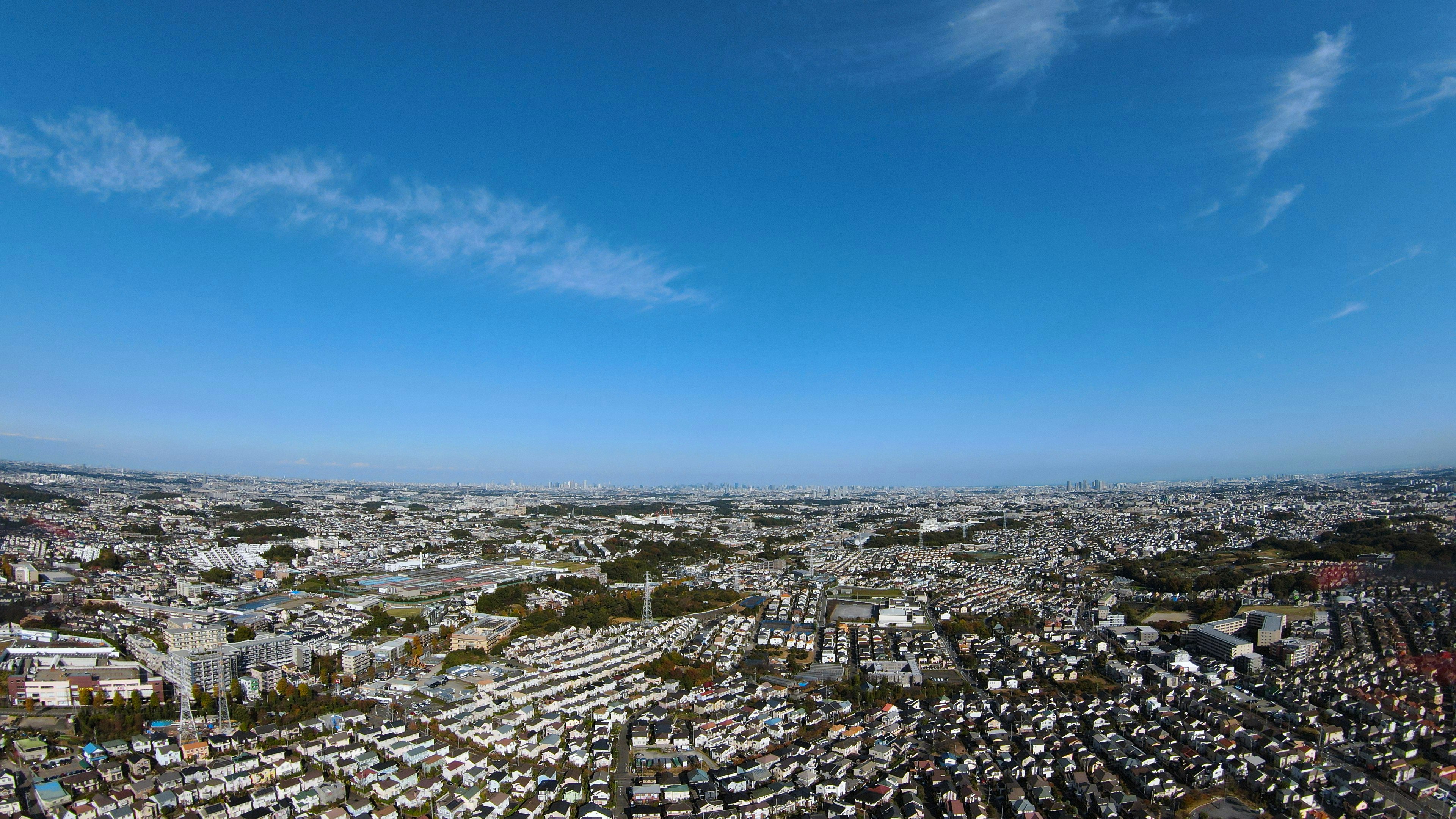 Pemandangan panorama kota yang luas di bawah langit biru dengan awan putih