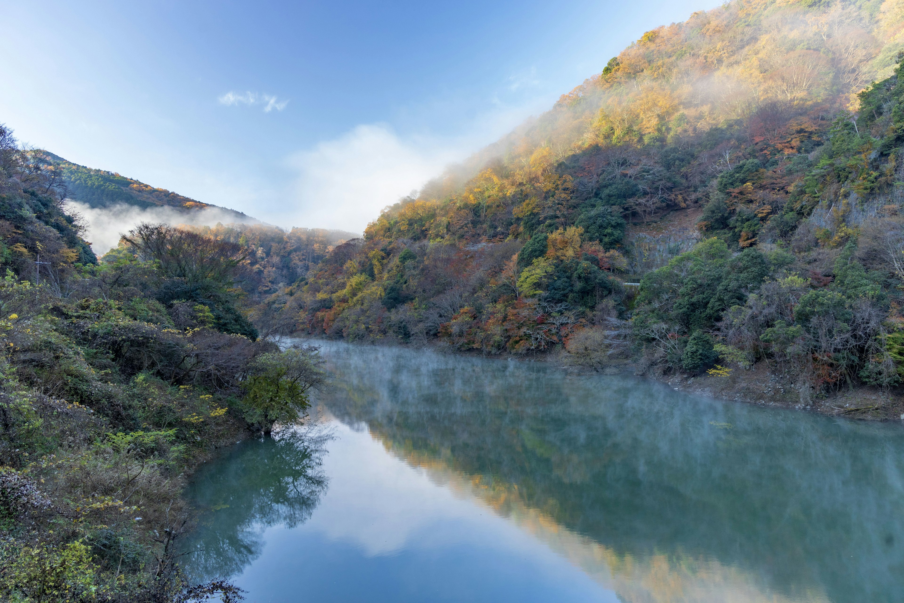 Ruhige Flusslandschaft umgeben von herbstlichem Laub und Bergen