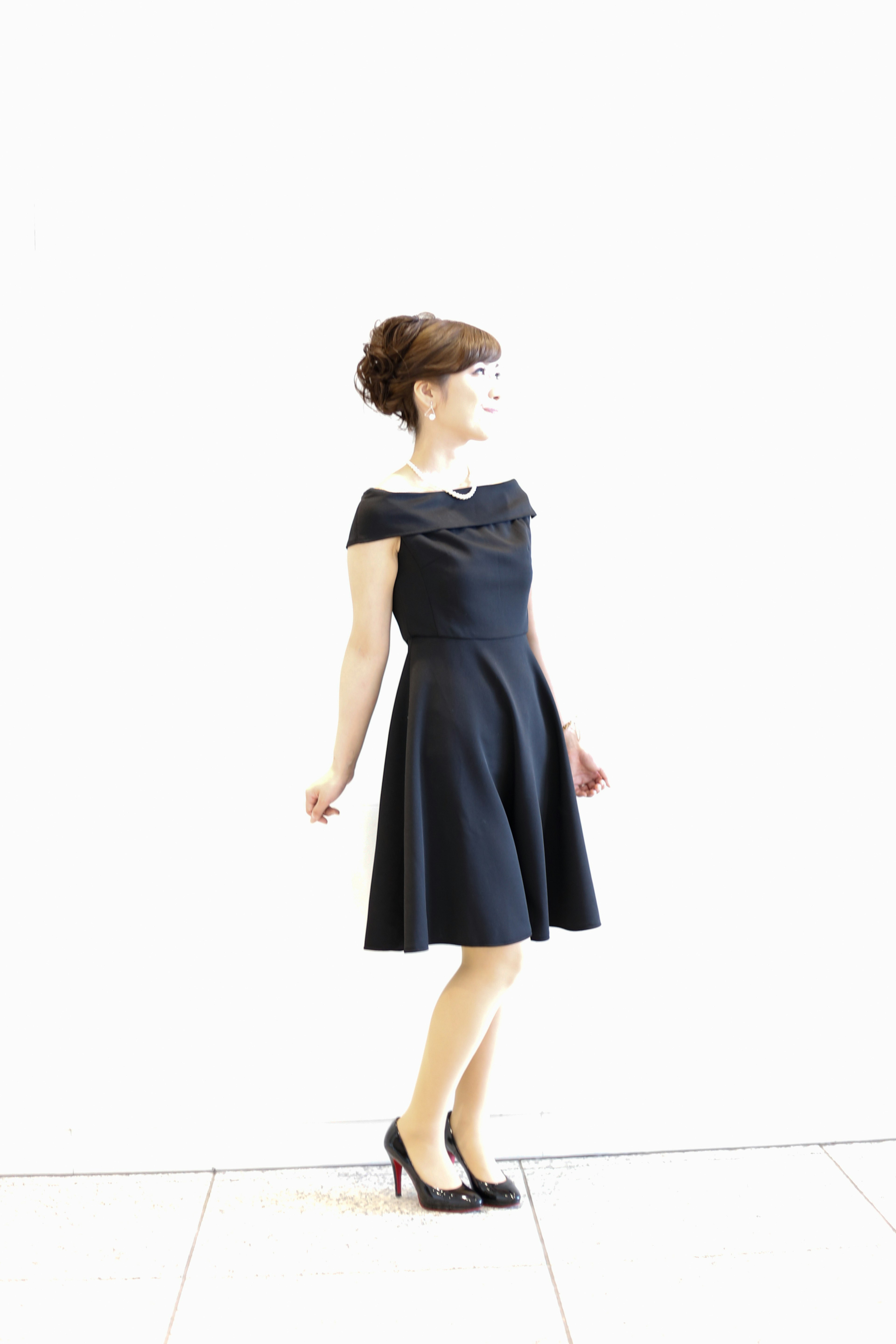 Woman in a black dress standing against a white background