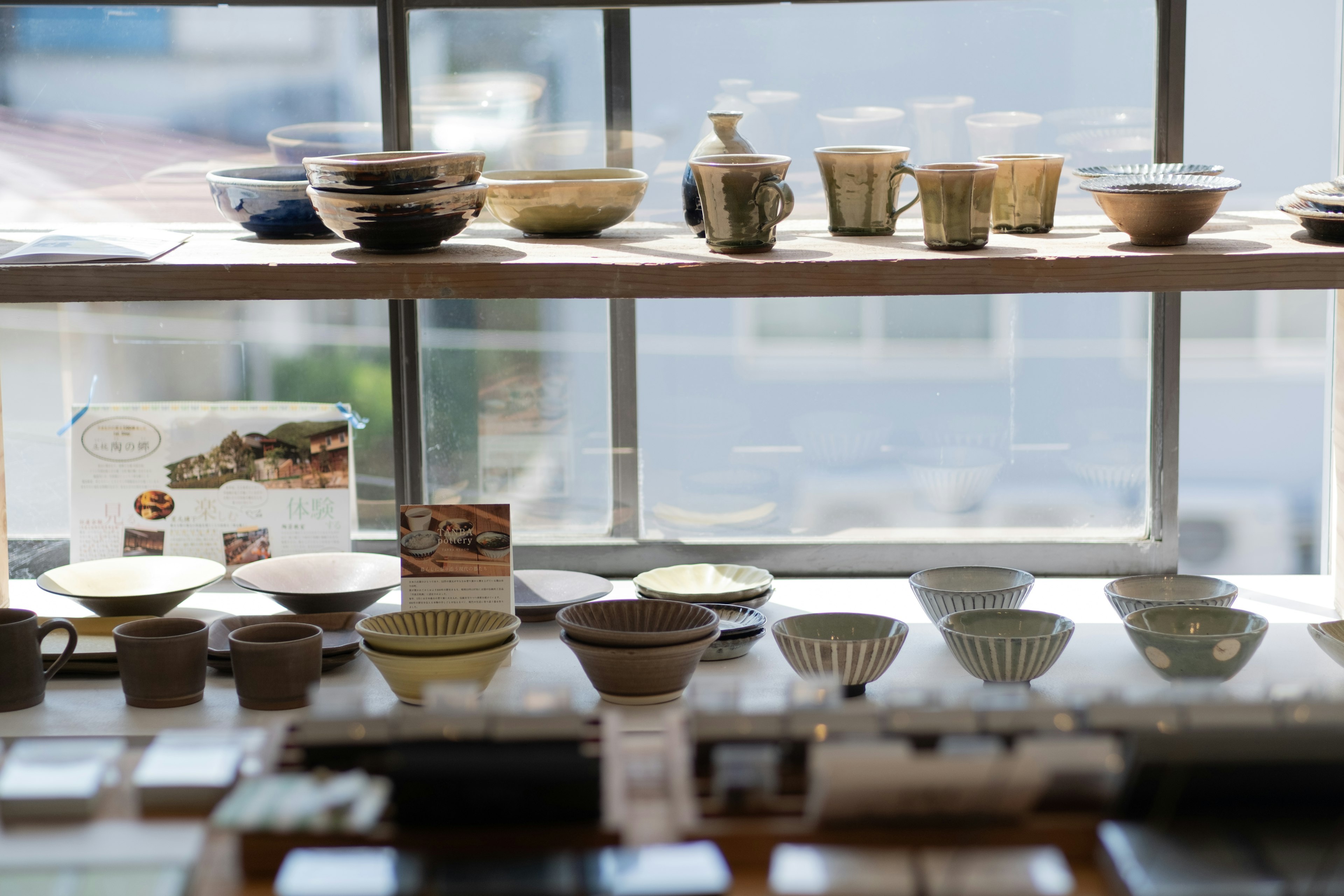 Display of ceramic bowls and plates arranged near a window