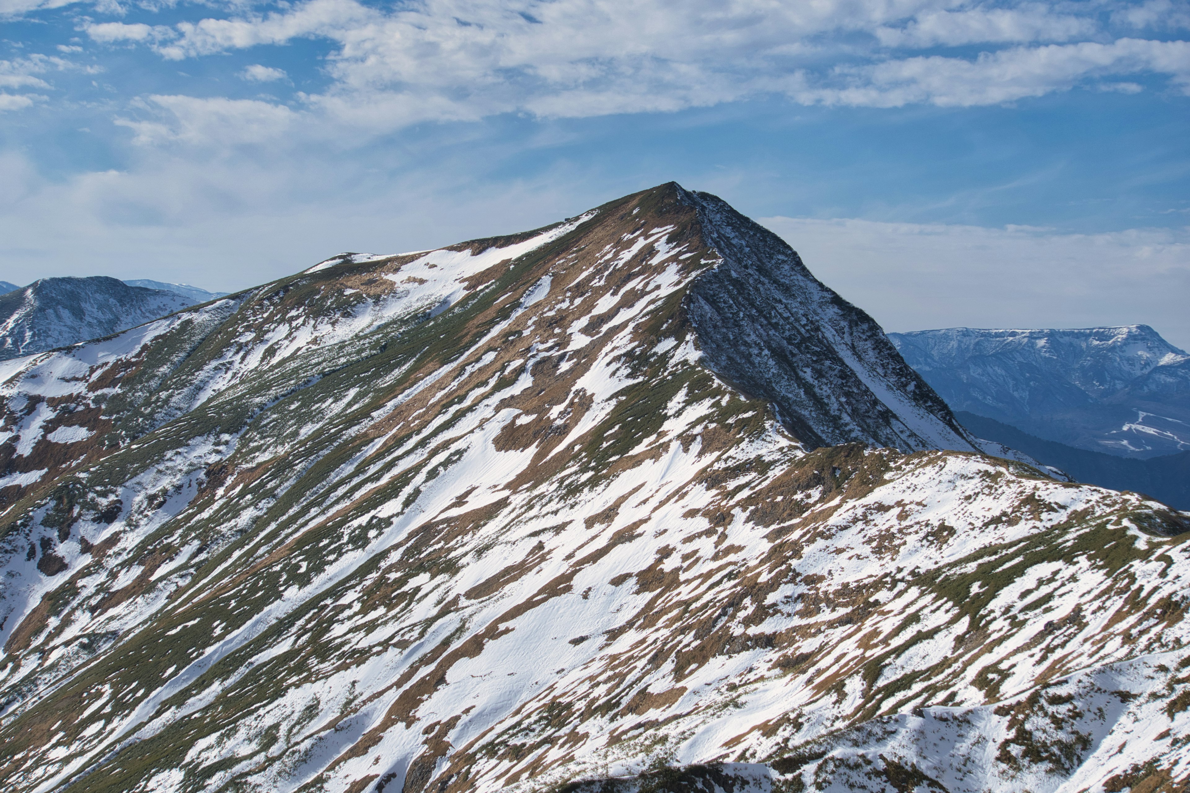 Picco di montagna coperto di neve sotto un cielo azzurro