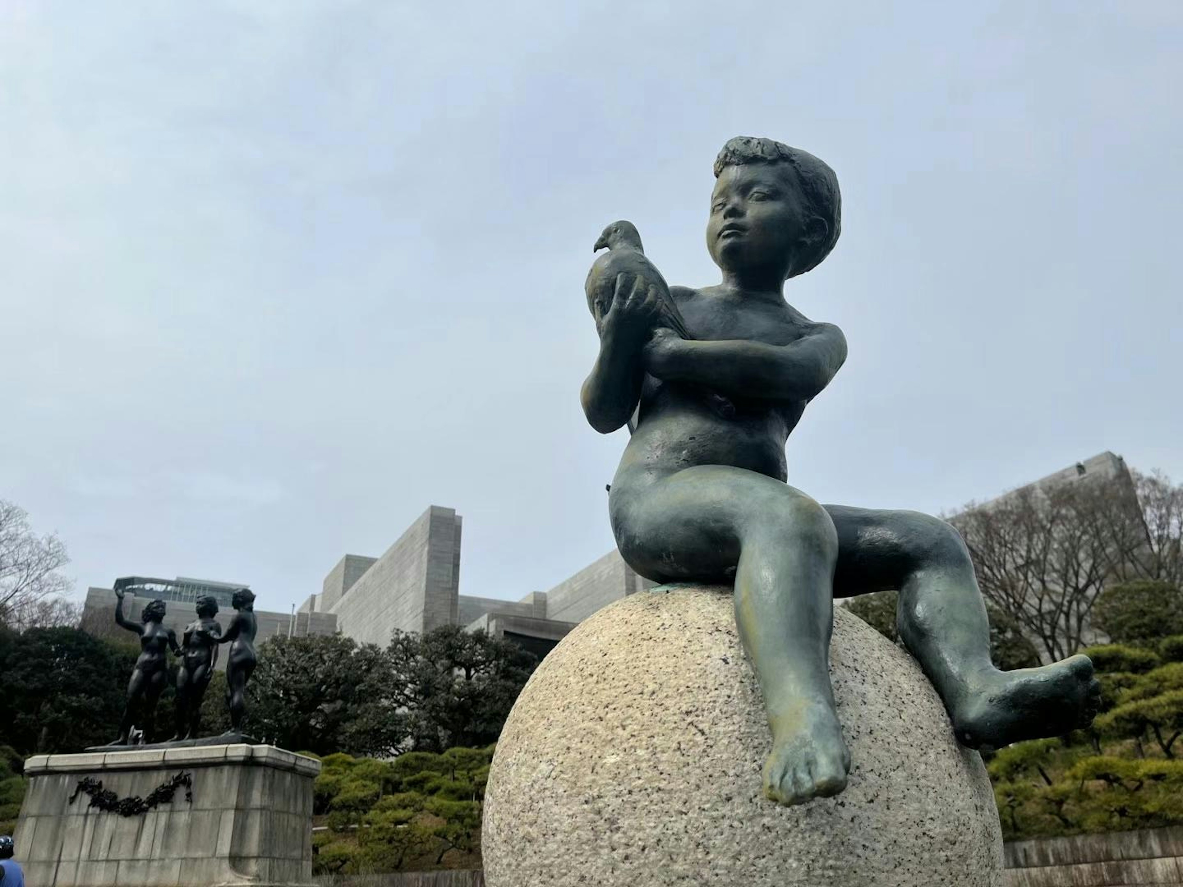 A boy sitting on a stone globe holding a bird