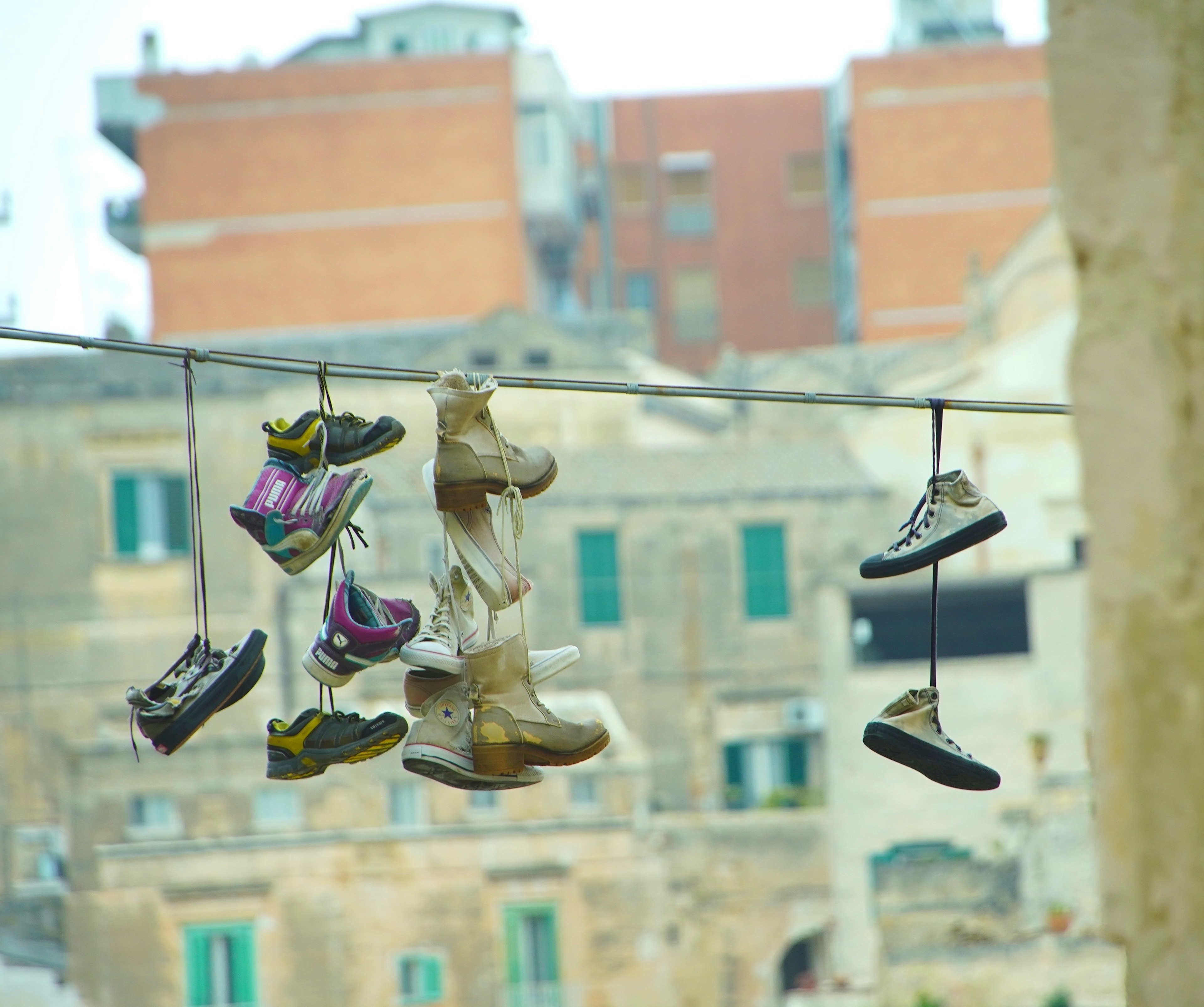 Chaussures suspendues sur une corde avec des vieux bâtiments en arrière-plan