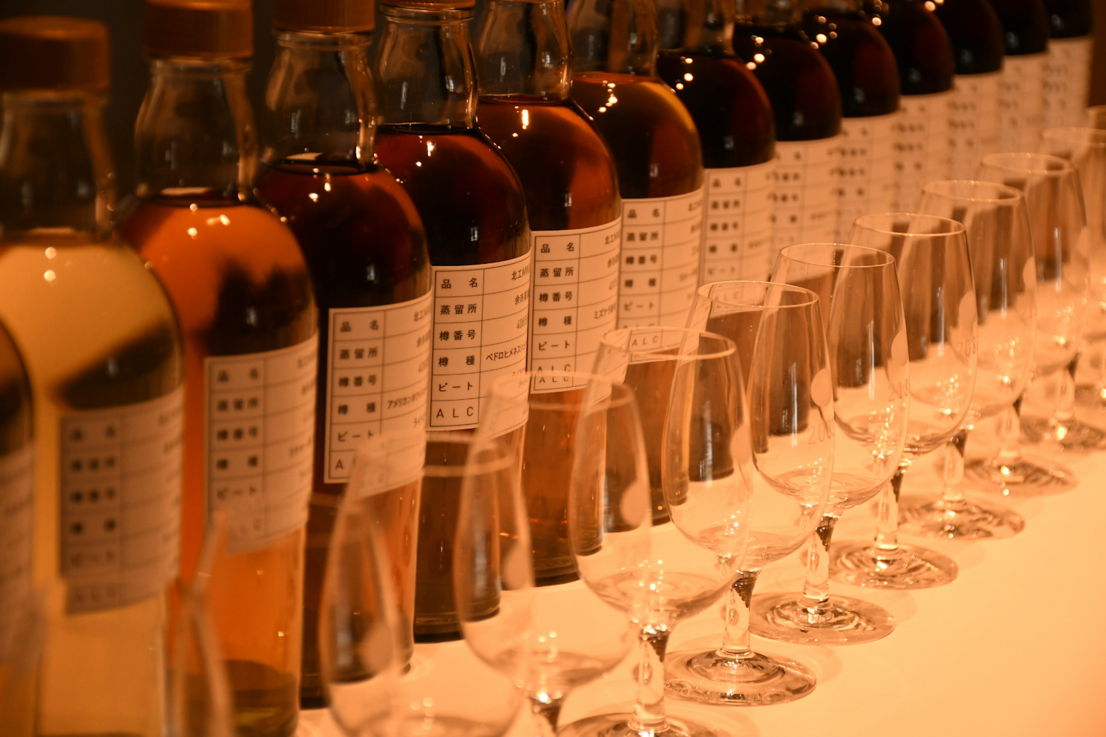 A row of bottles and glasses arranged on a table