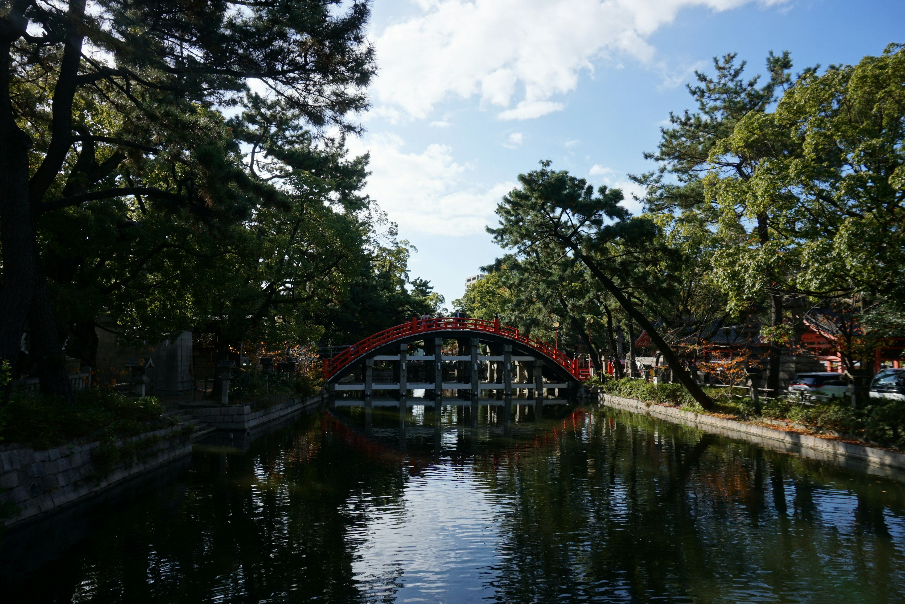 Puente rojo sobre agua tranquila reflejando el cielo