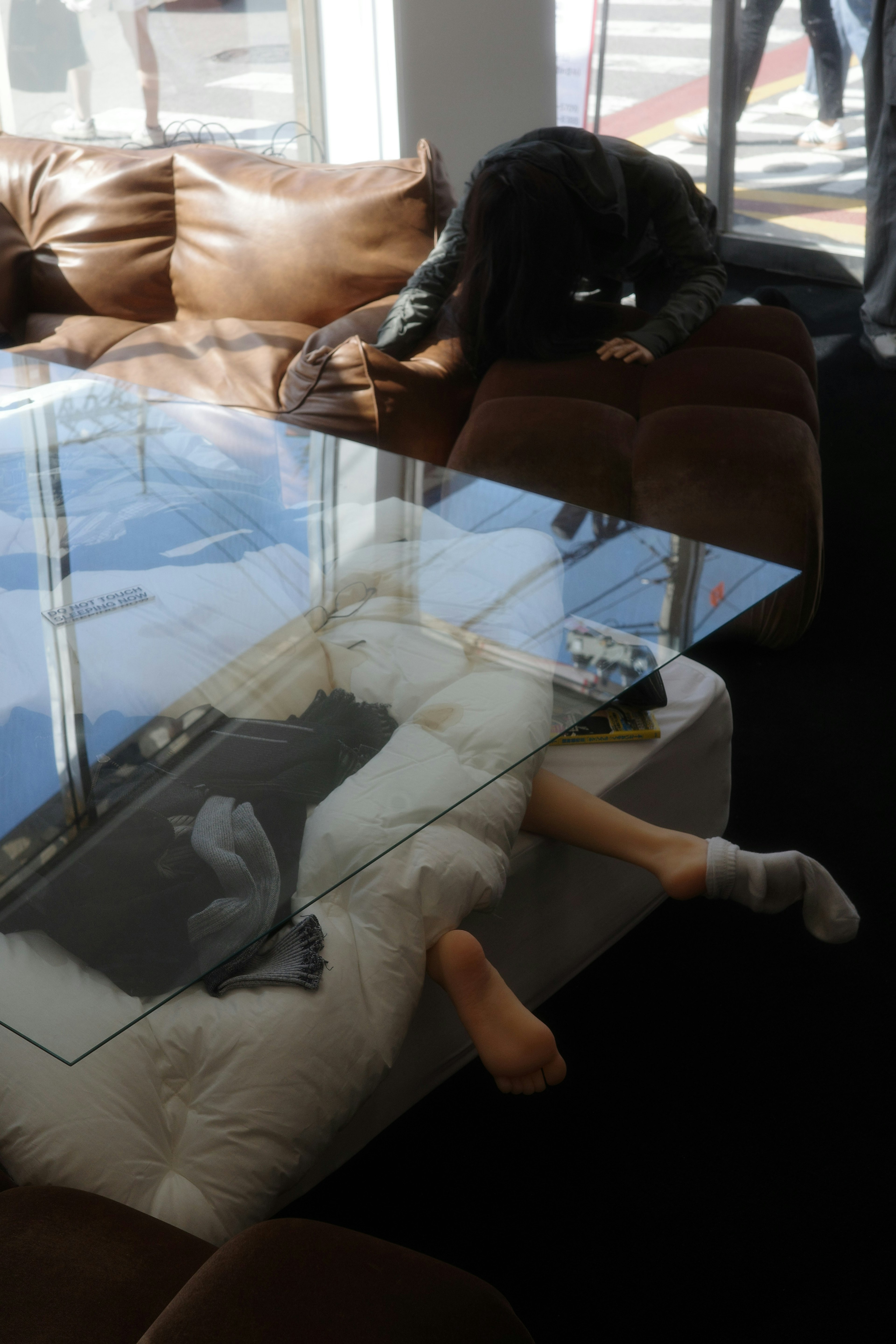 Reflection of a person on a glass-top table with a sofa