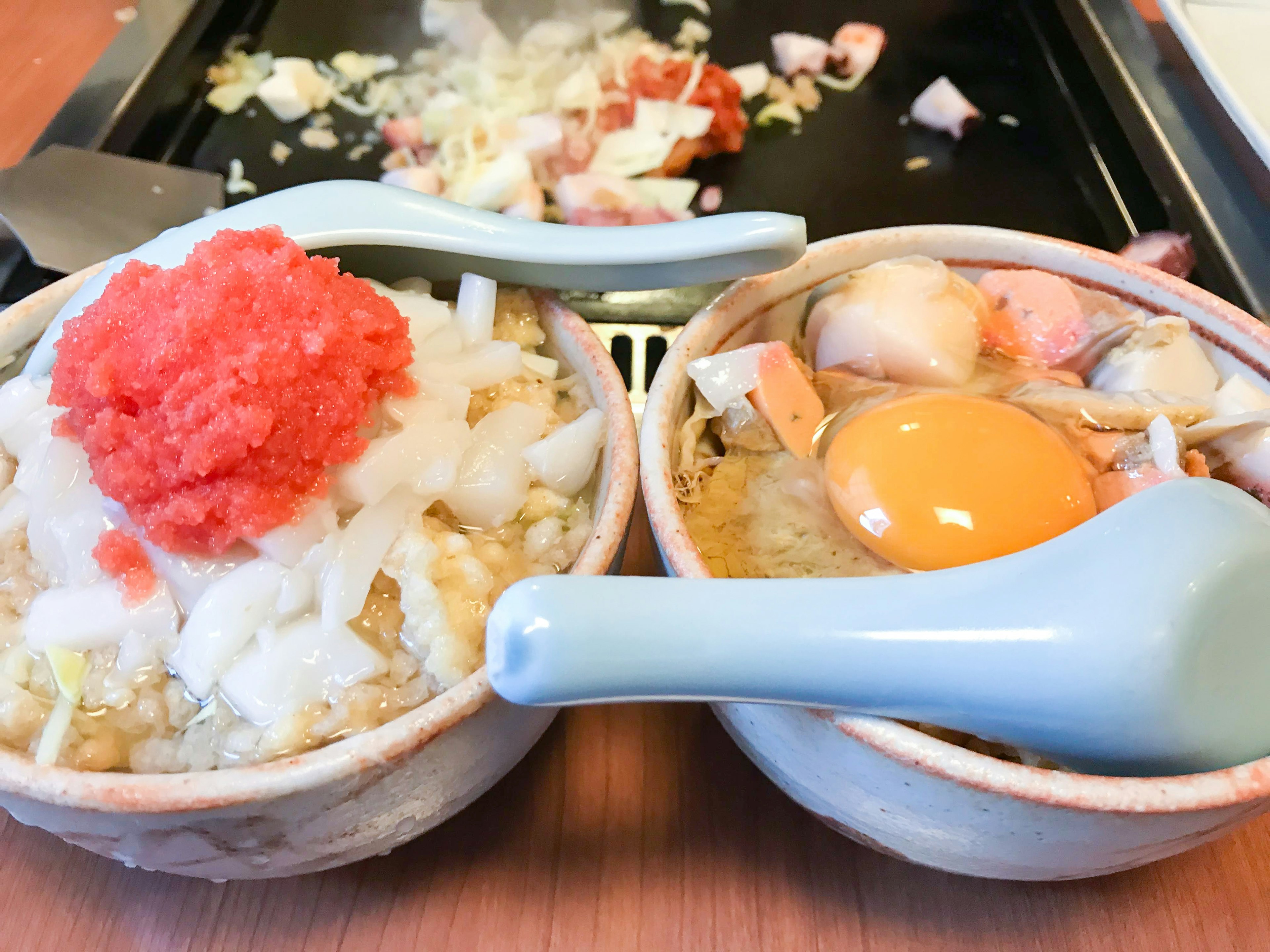 Two small bowls of food One topped with red fish roe and white ingredients The other containing an egg and seafood