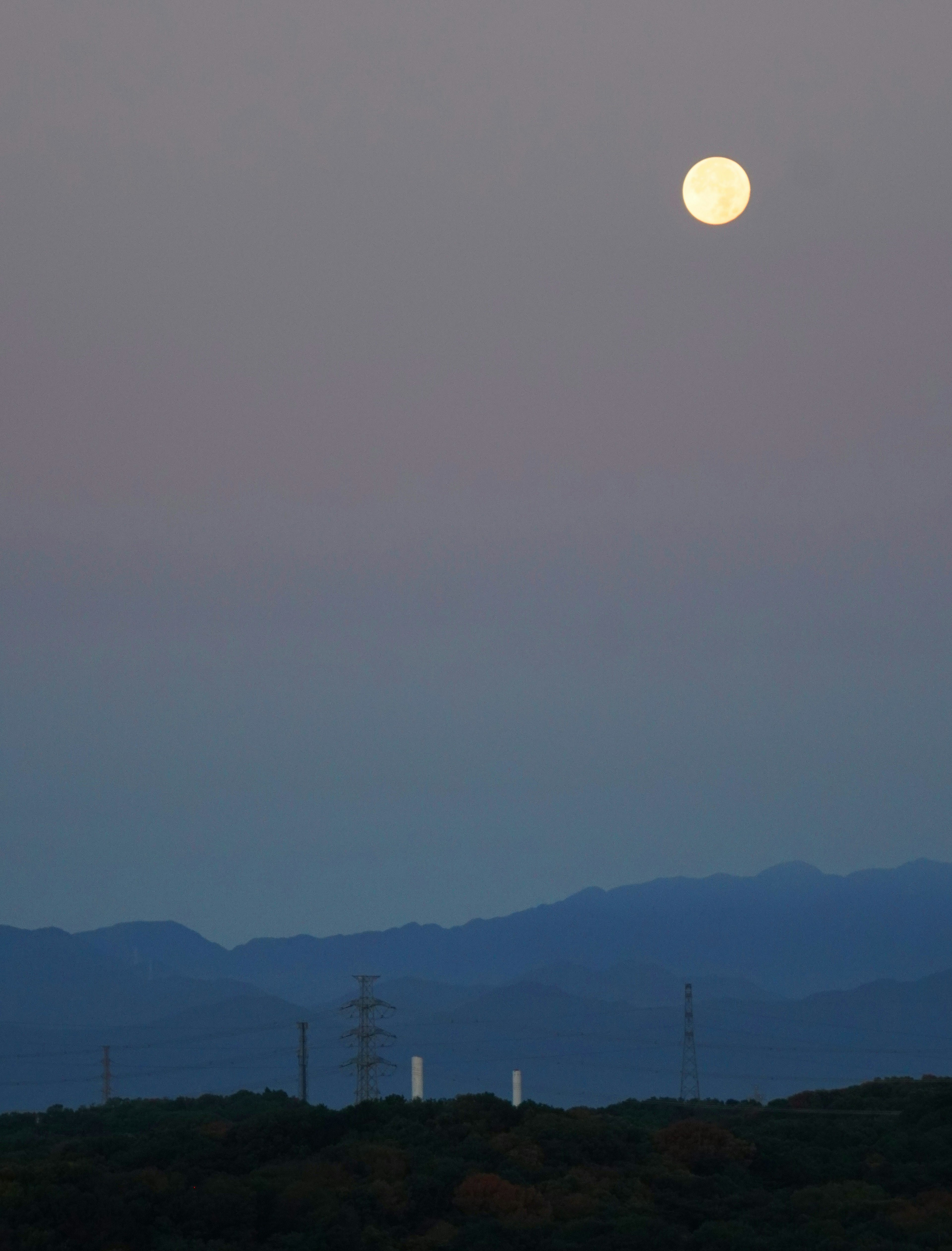 Pleine lune dans le ciel du soir avec des silhouettes de montagnes