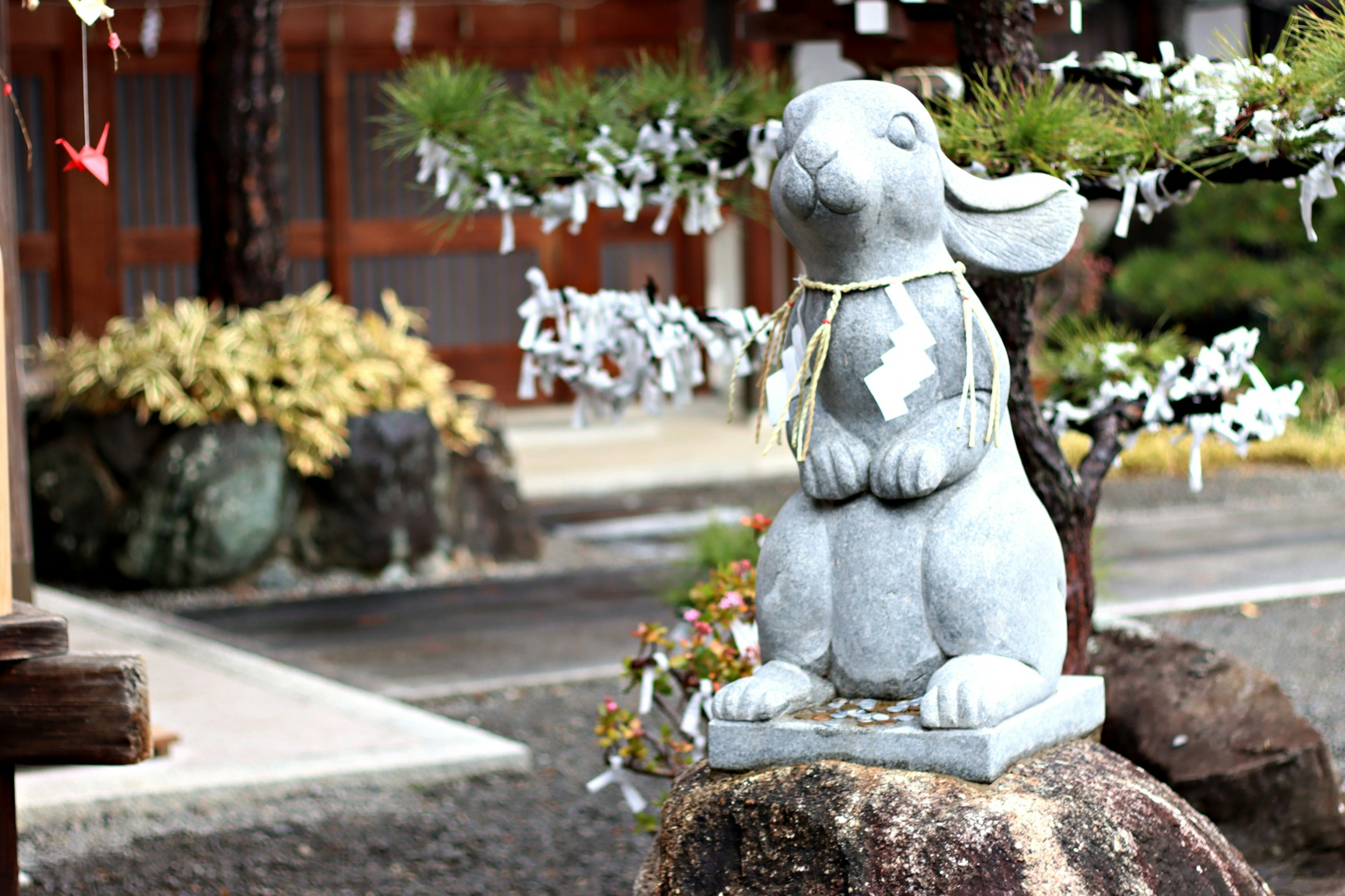 Eine Steinstatue eines Kaninchens steht in einem Garten