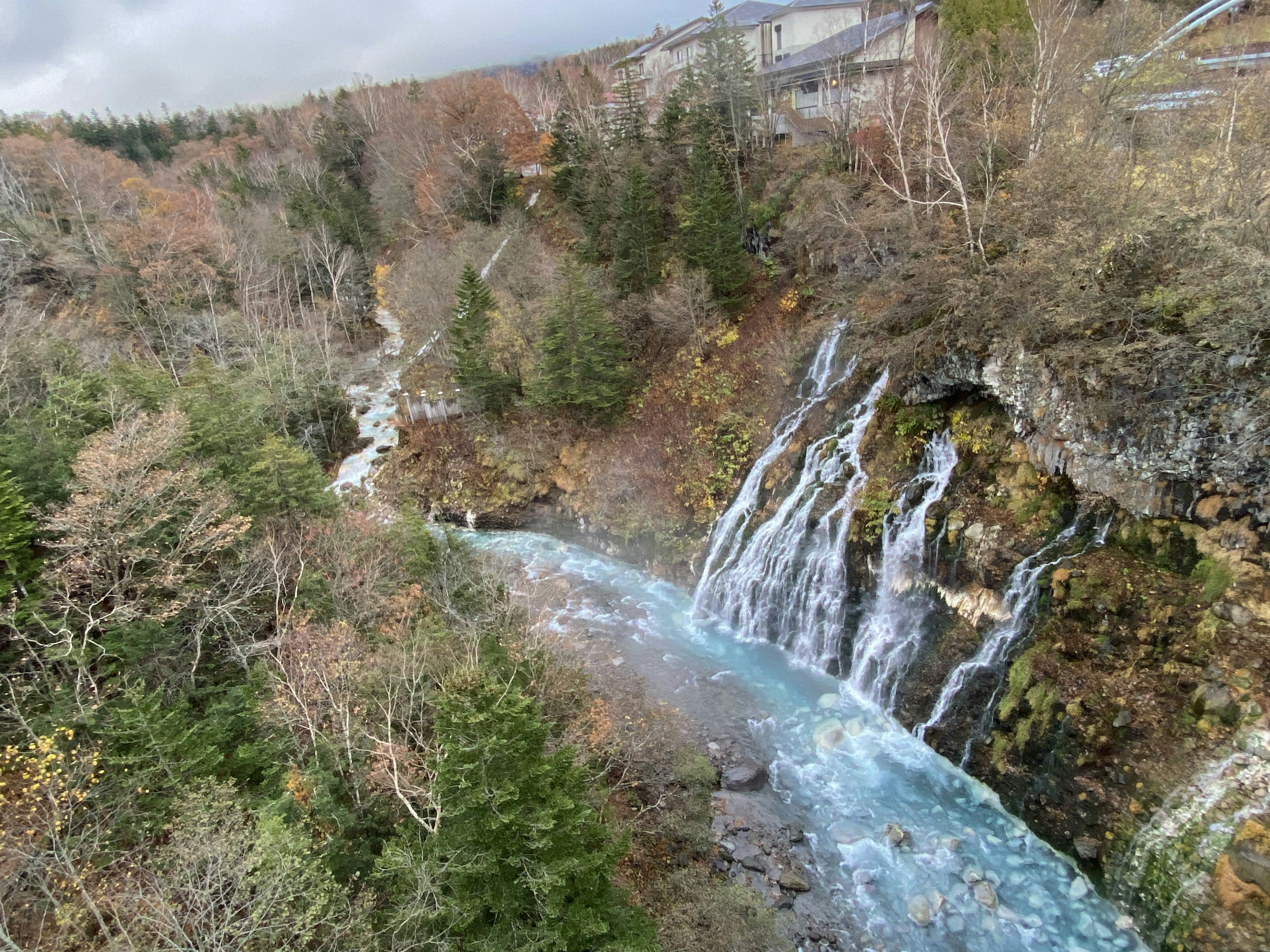 Una hermosa cascada que fluye hacia un río rodeado de follaje de otoño