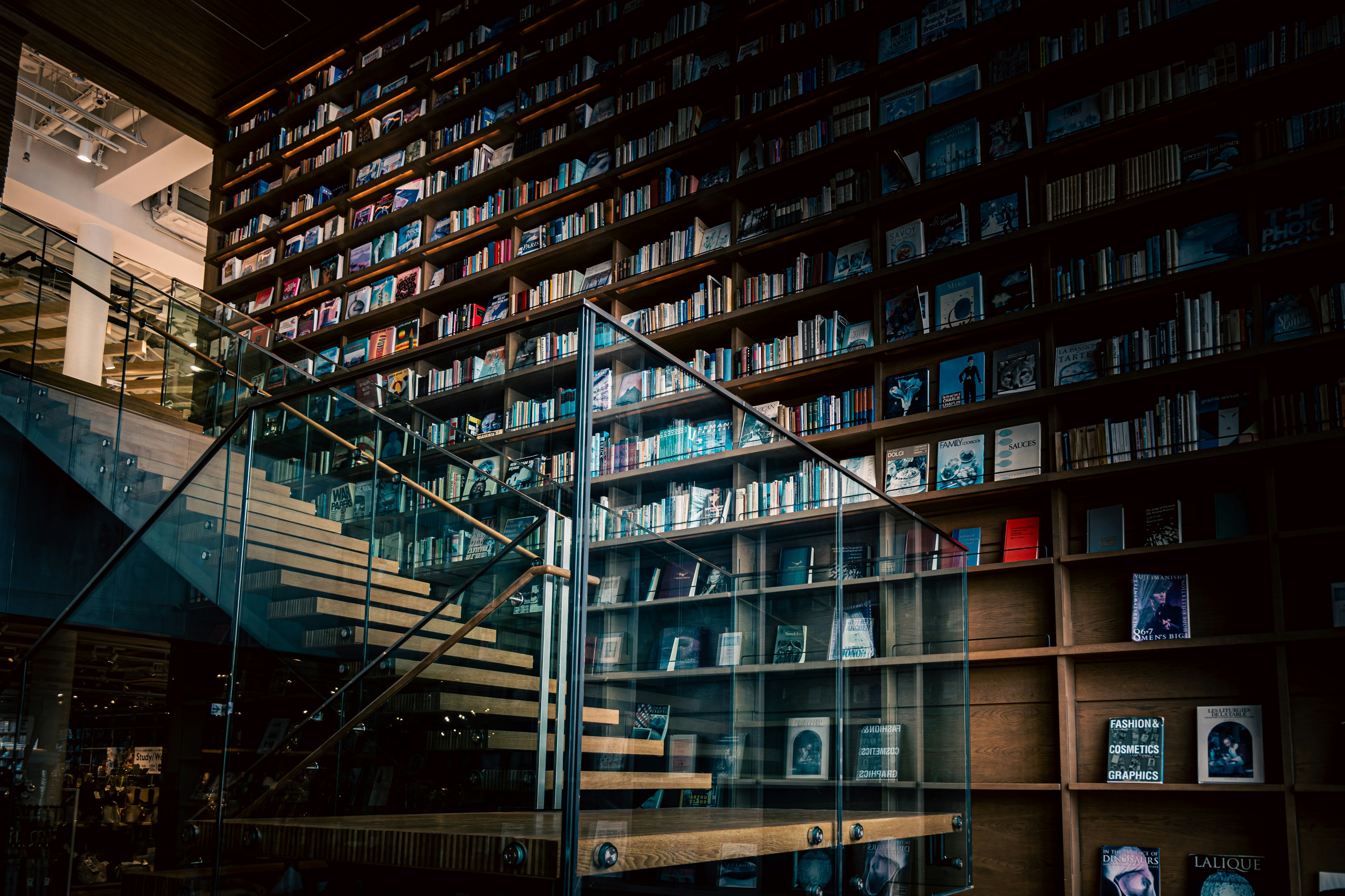 Intérieur moderne d'une bibliothèque avec un escalier en verre et des étagères