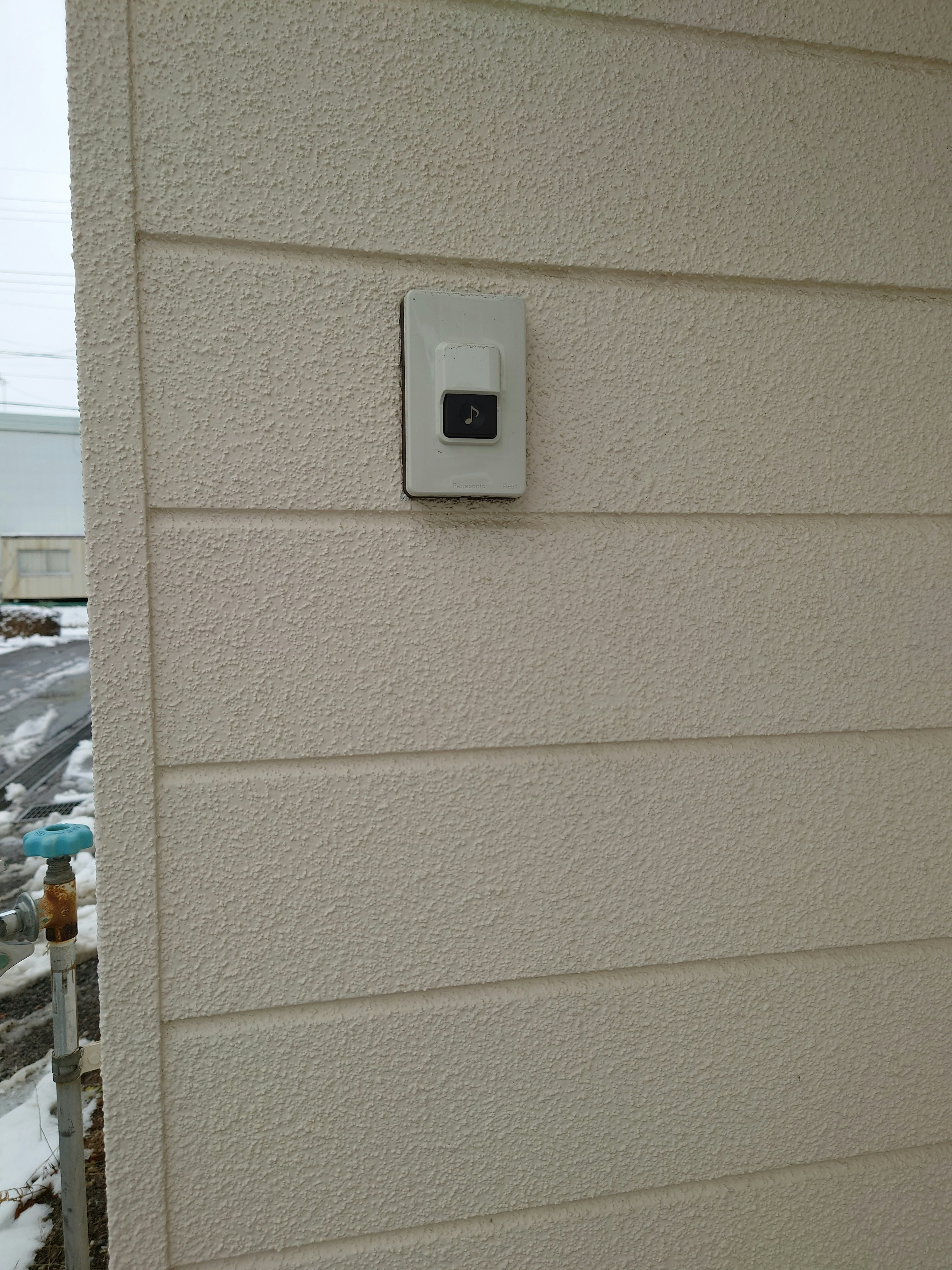 A wall-mounted intercom on a white textured wall