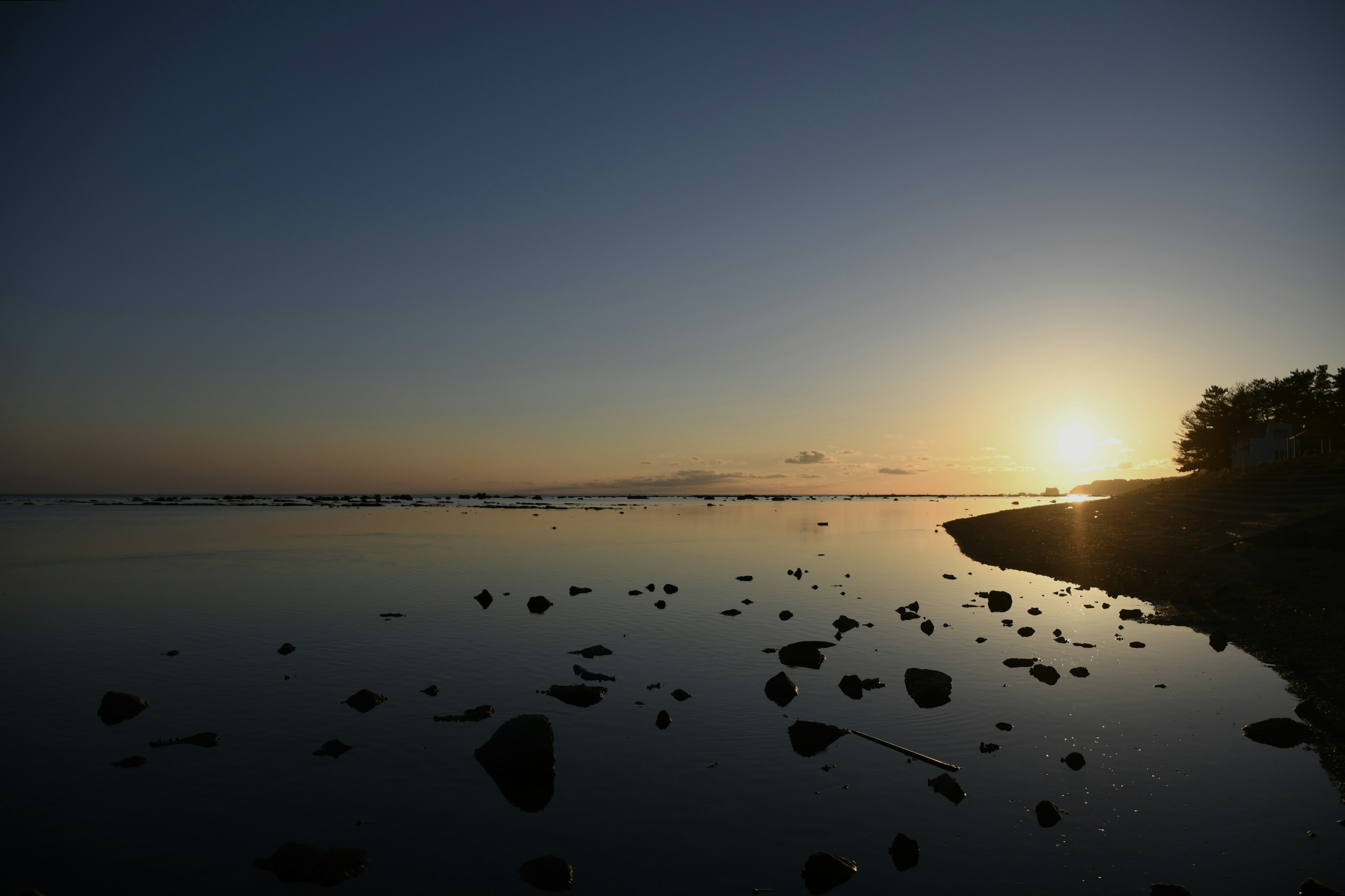 Paysage côtier serein avec un coucher de soleil sur des eaux calmes