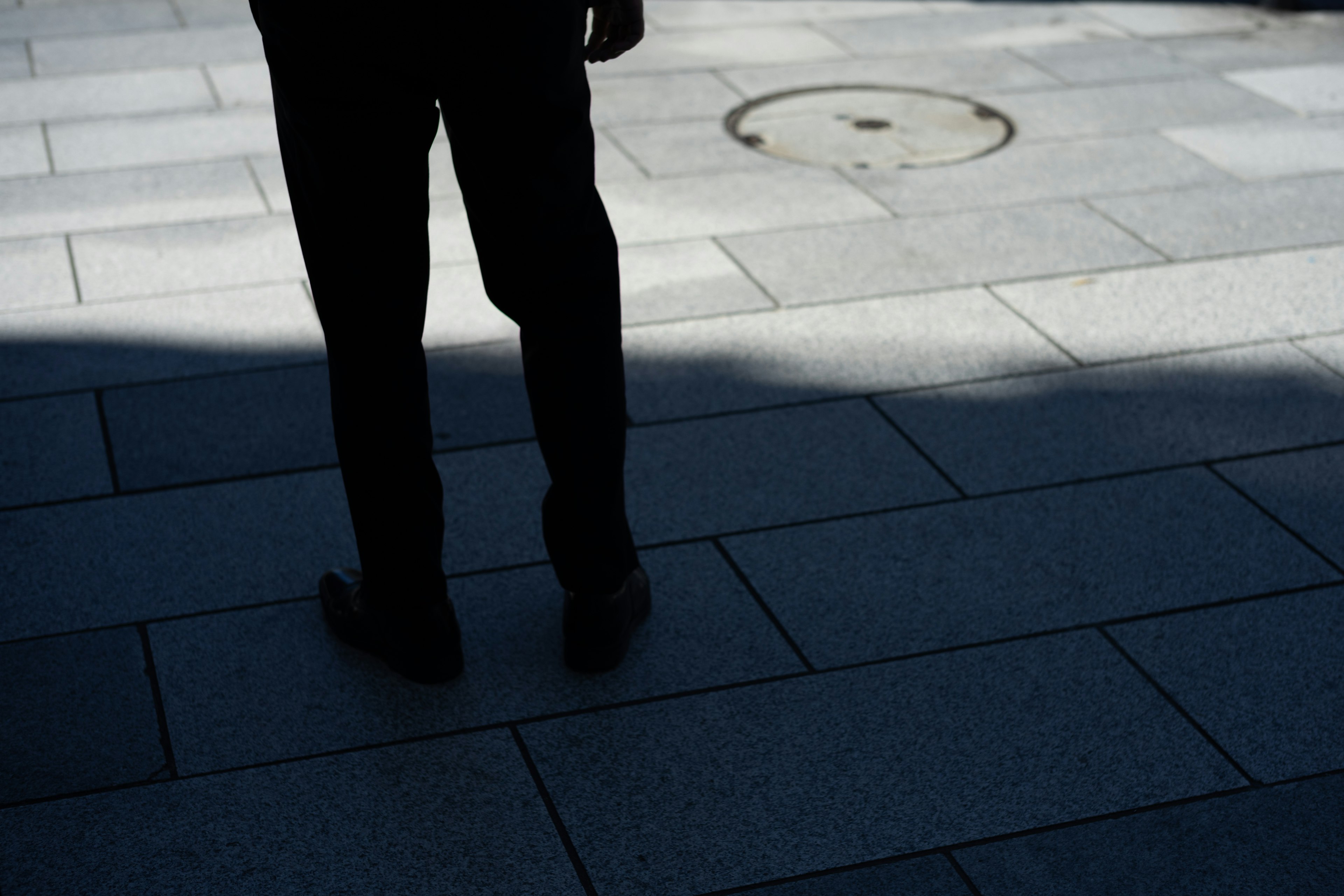 Silhouette of a person standing on a stone pavement with shadows