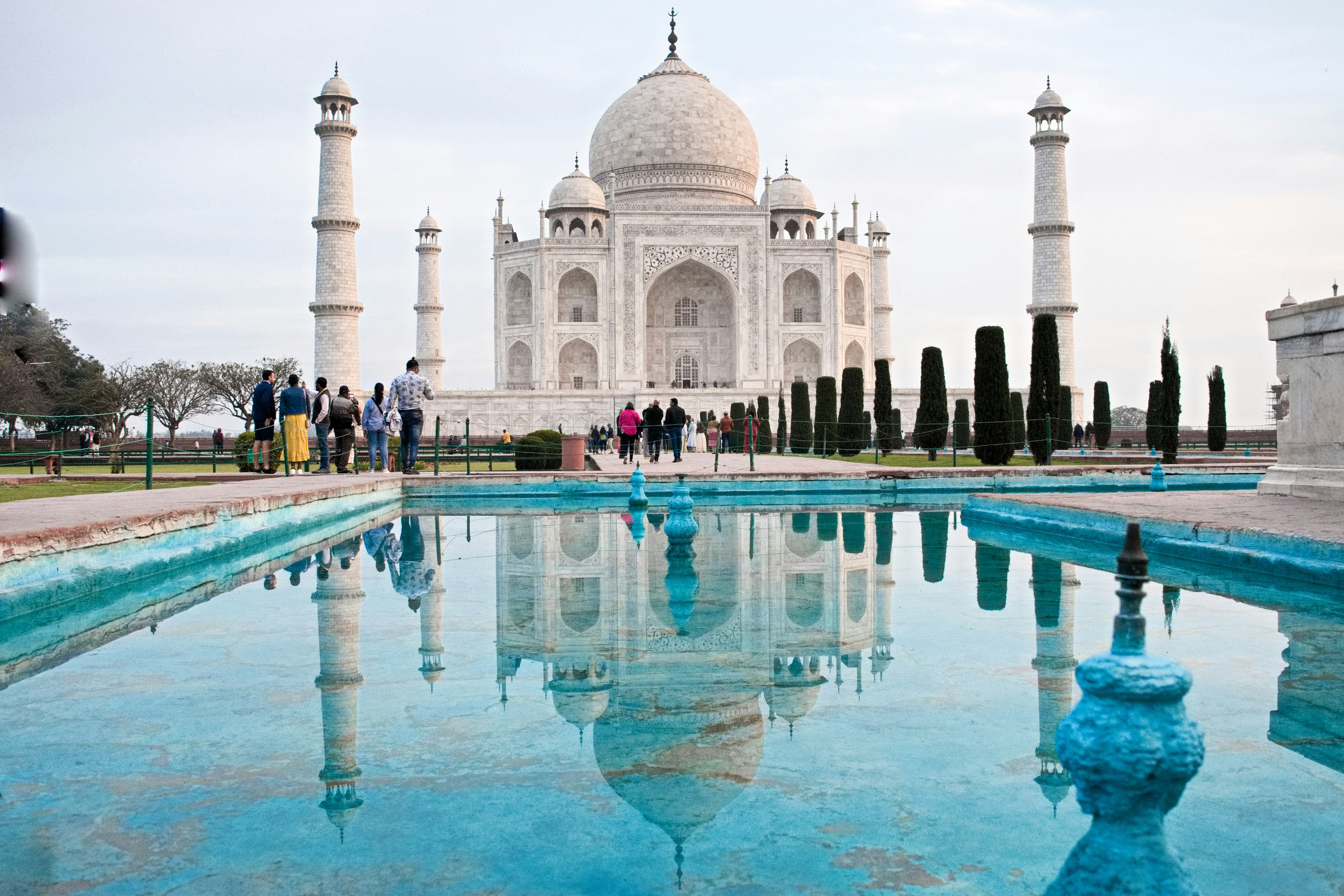 Blick auf das Taj Mahal mit Reflexion im Wasser und Besuchern im Vordergrund