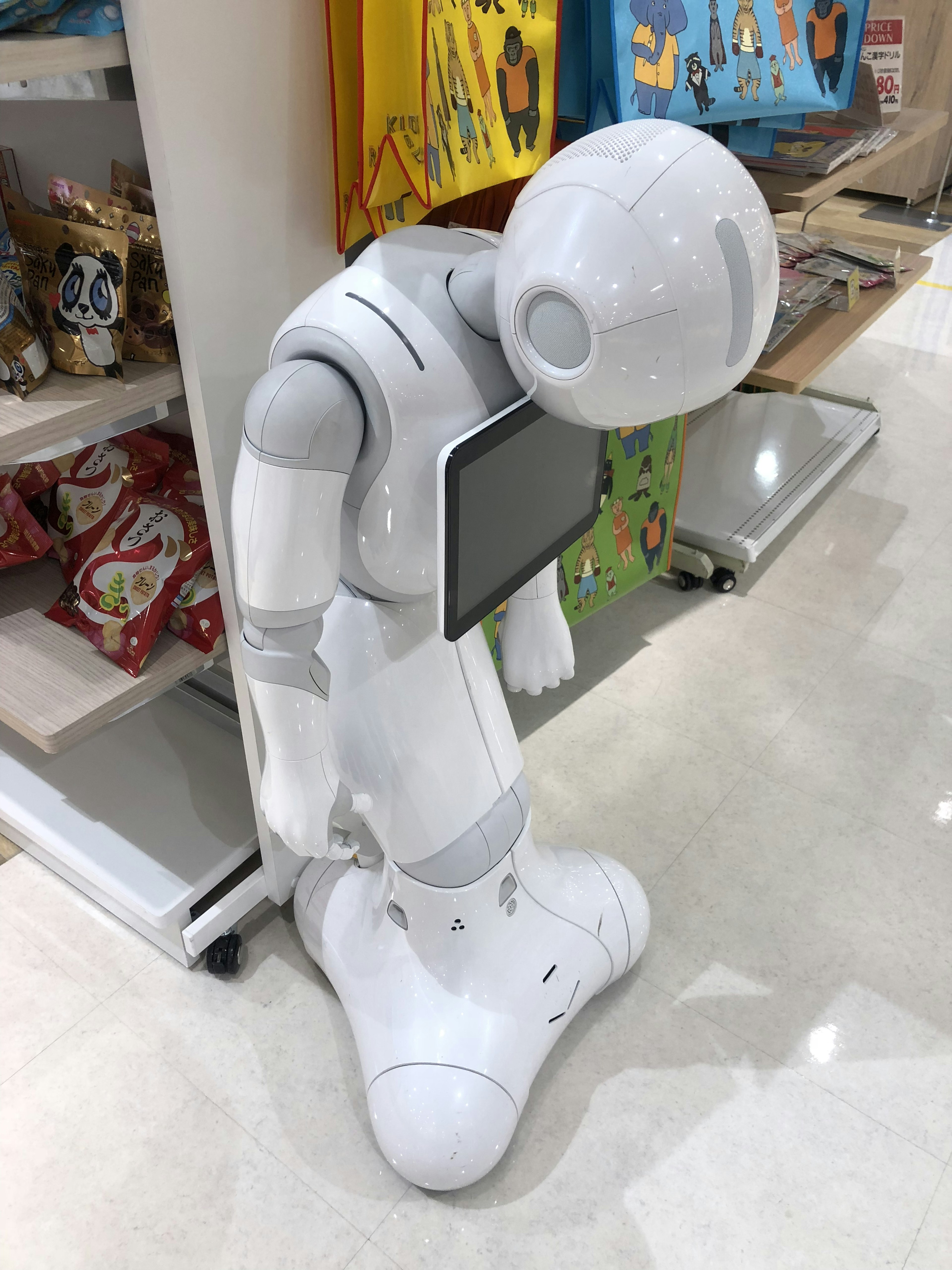 Un robot blanc se penchant en avant tenant une tablette