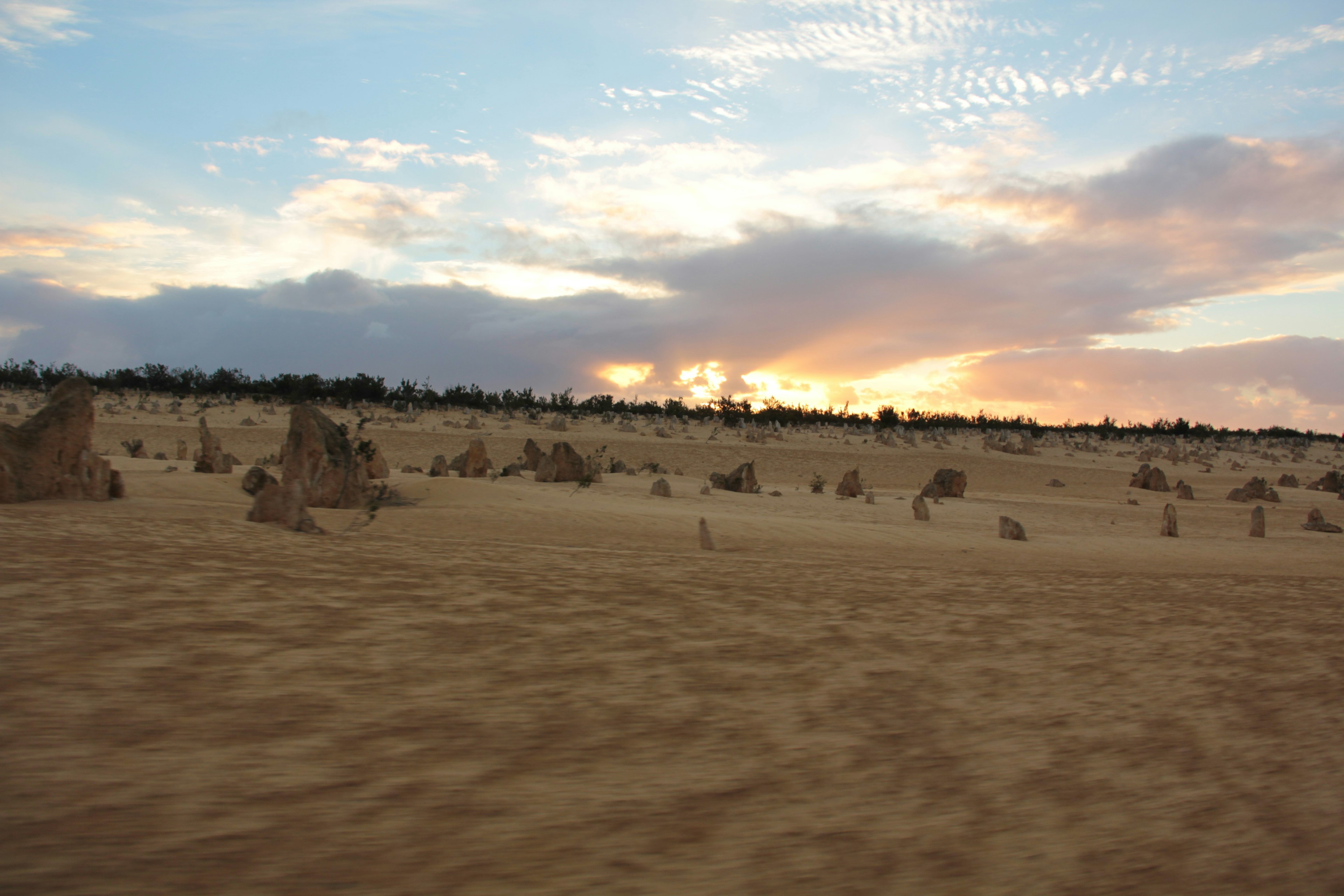 Paysage avec des formations rocheuses uniques éparpillées dans le sable avec un coucher de soleil coloré