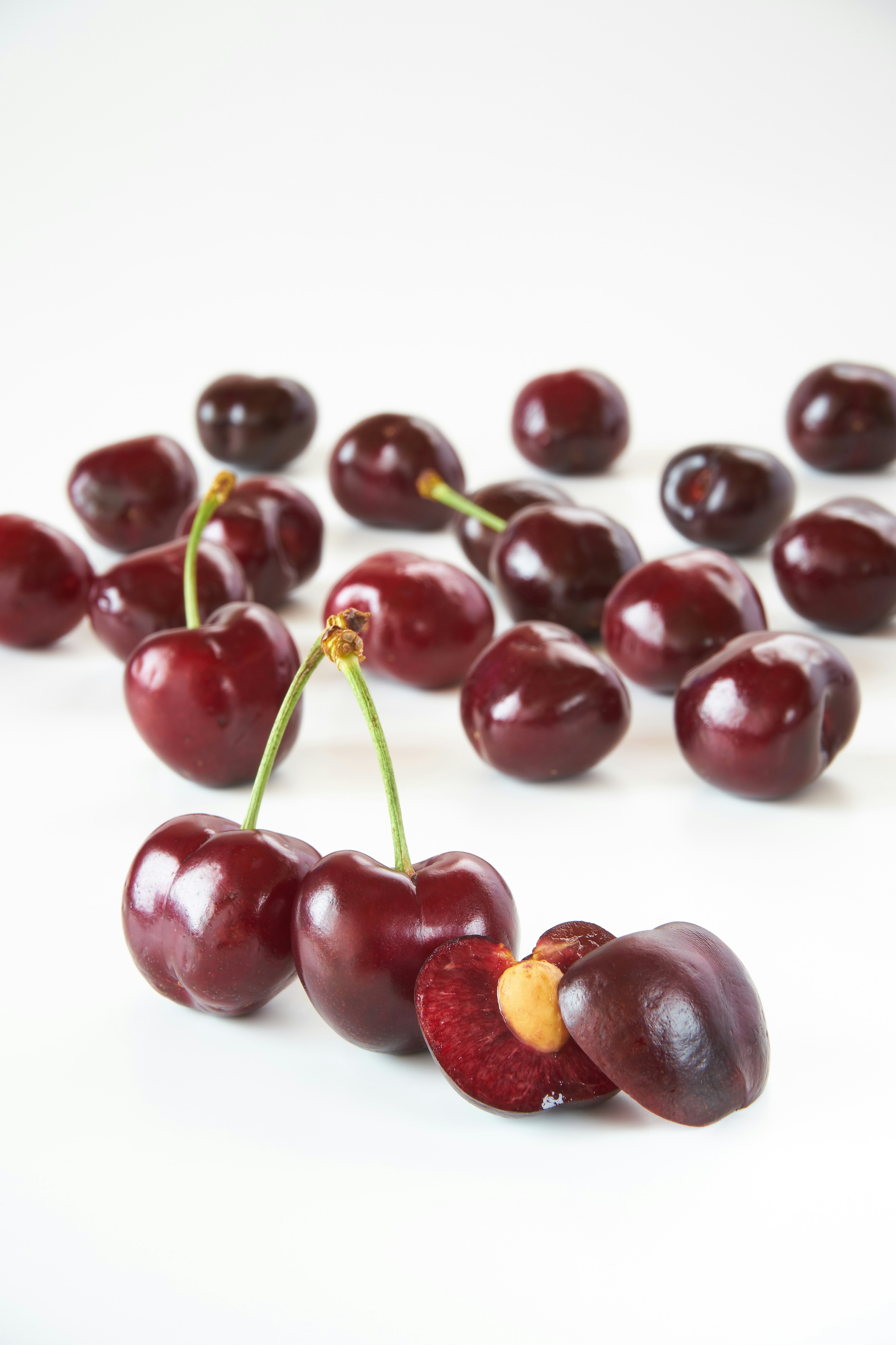 Close-up of vibrant red cherries with a cut cherry showing its pit