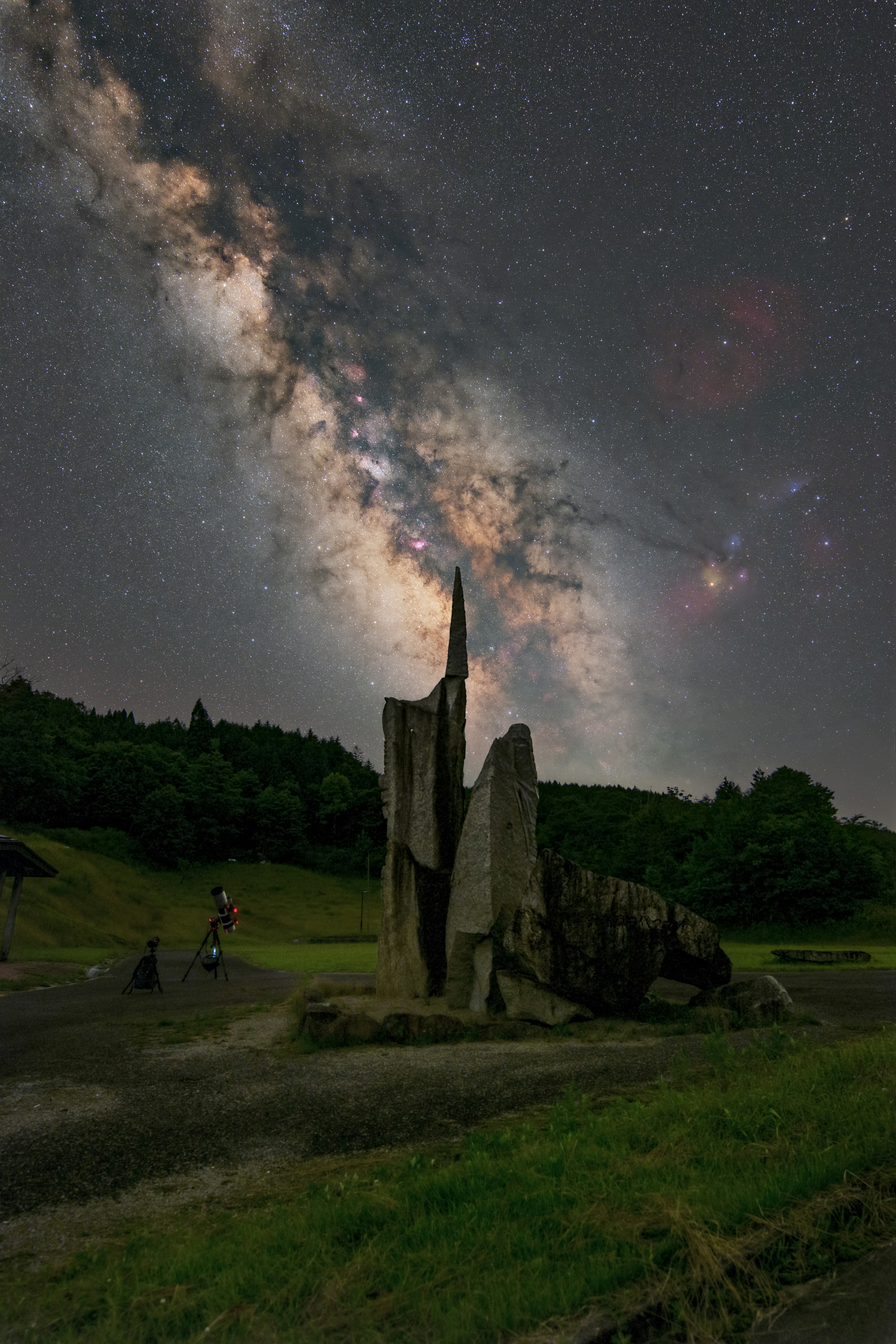 A stunning night scene featuring a large rock and sculptural structure under a starry sky