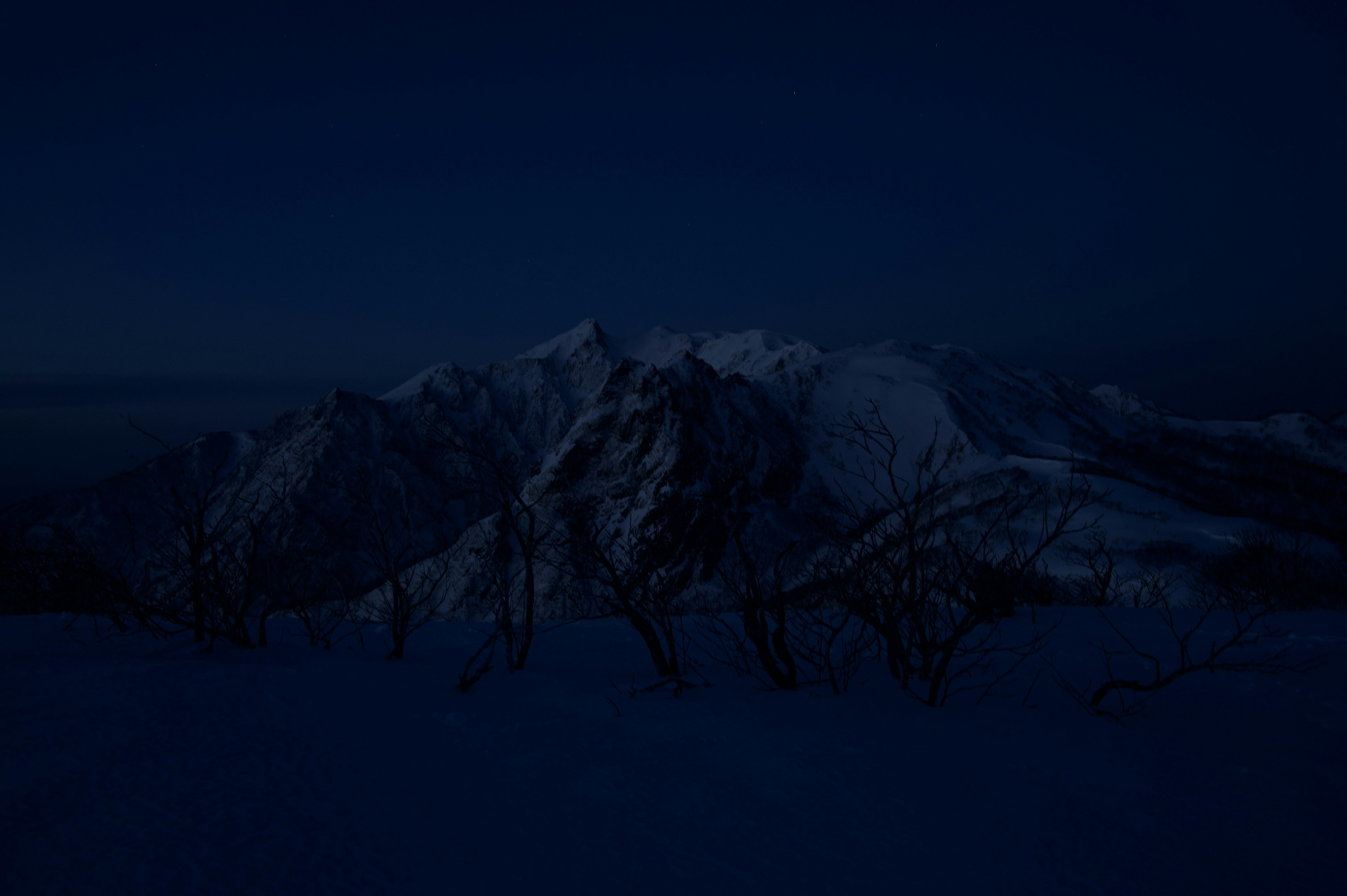 Snow-covered mountains under a dark night sky