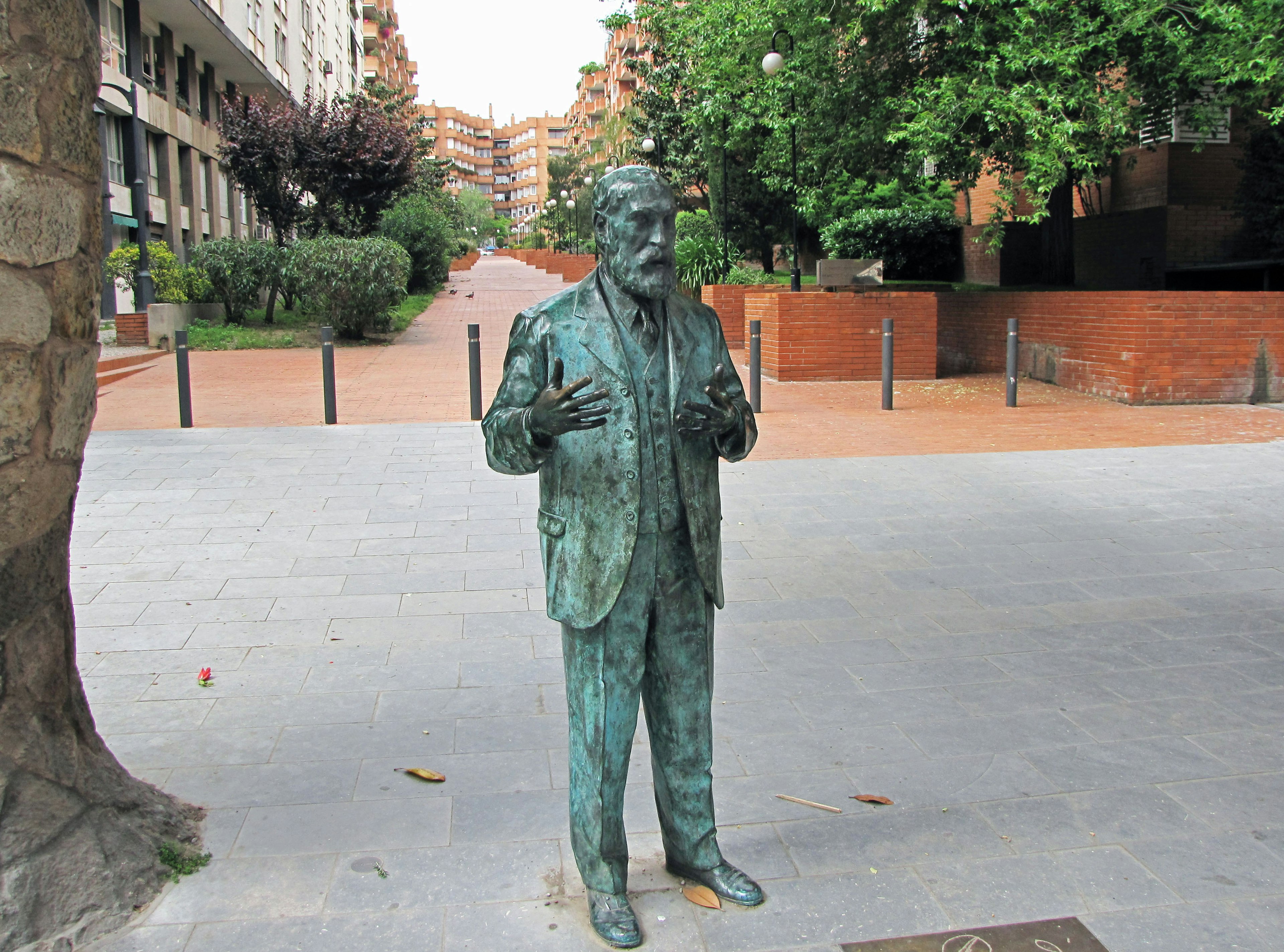 Bronze statue of a man standing in a park with outstretched hands