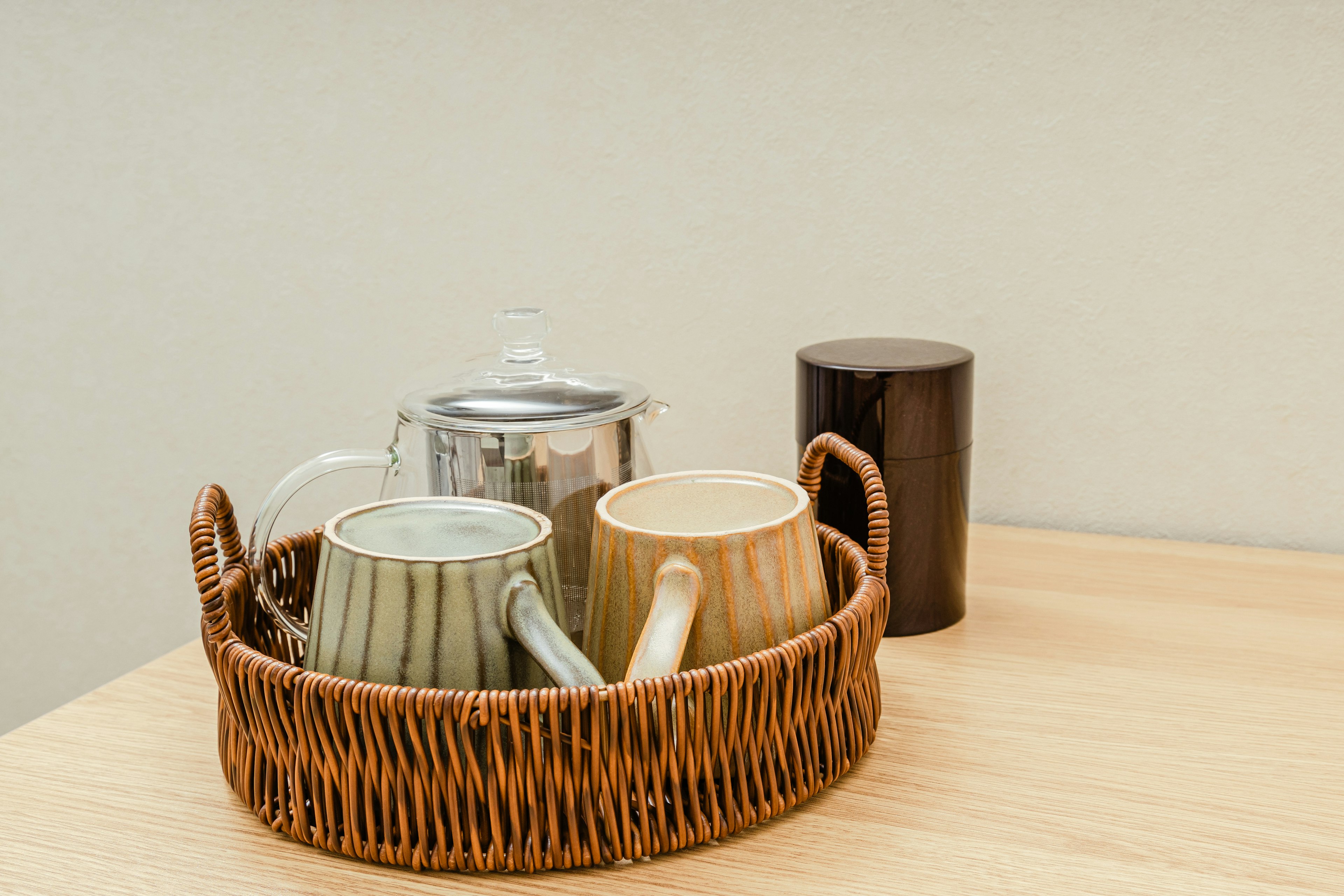 A set of teapot and mugs on a wicker tray