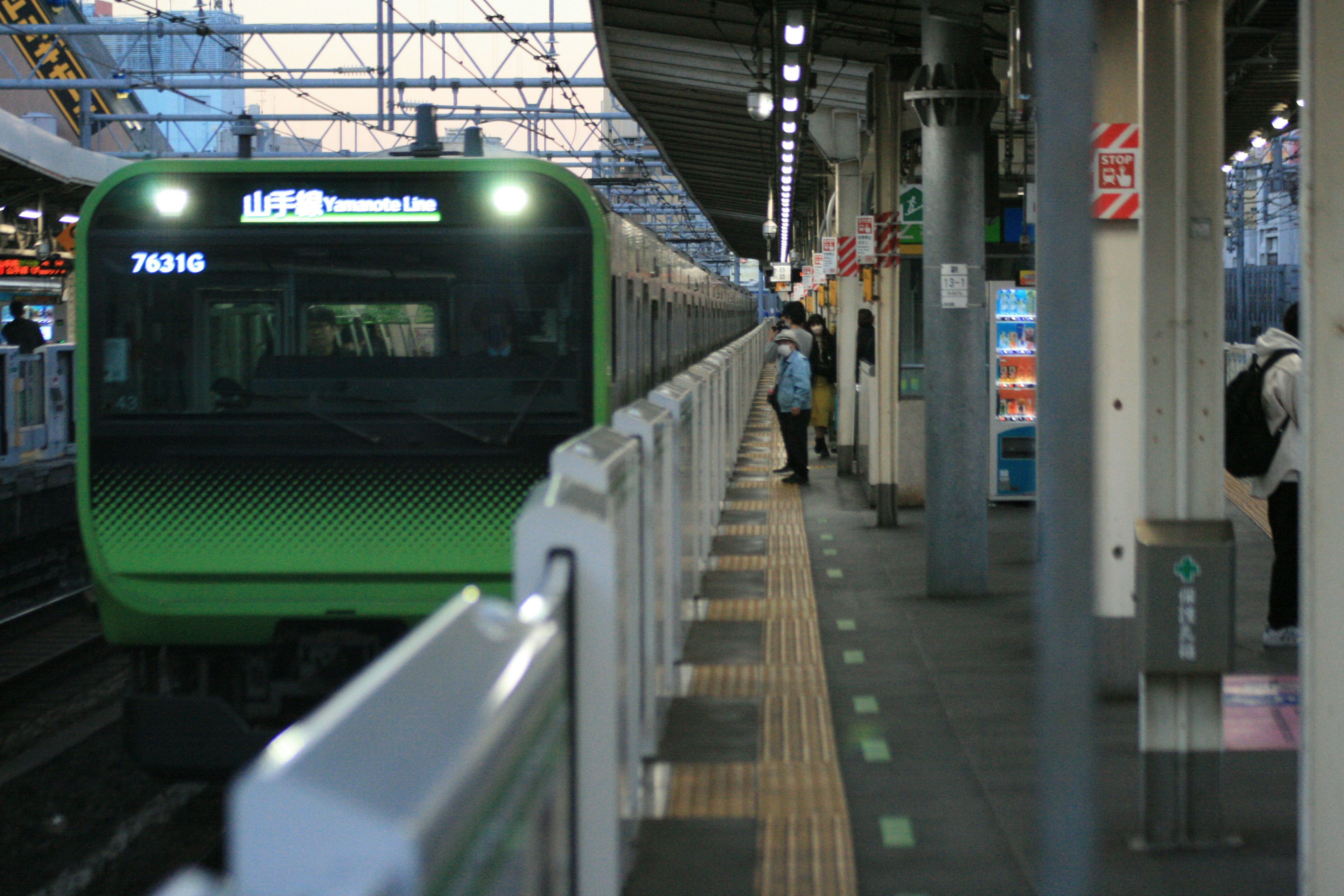 Un tren verde está detenido en una estación con un pasajero en el andén