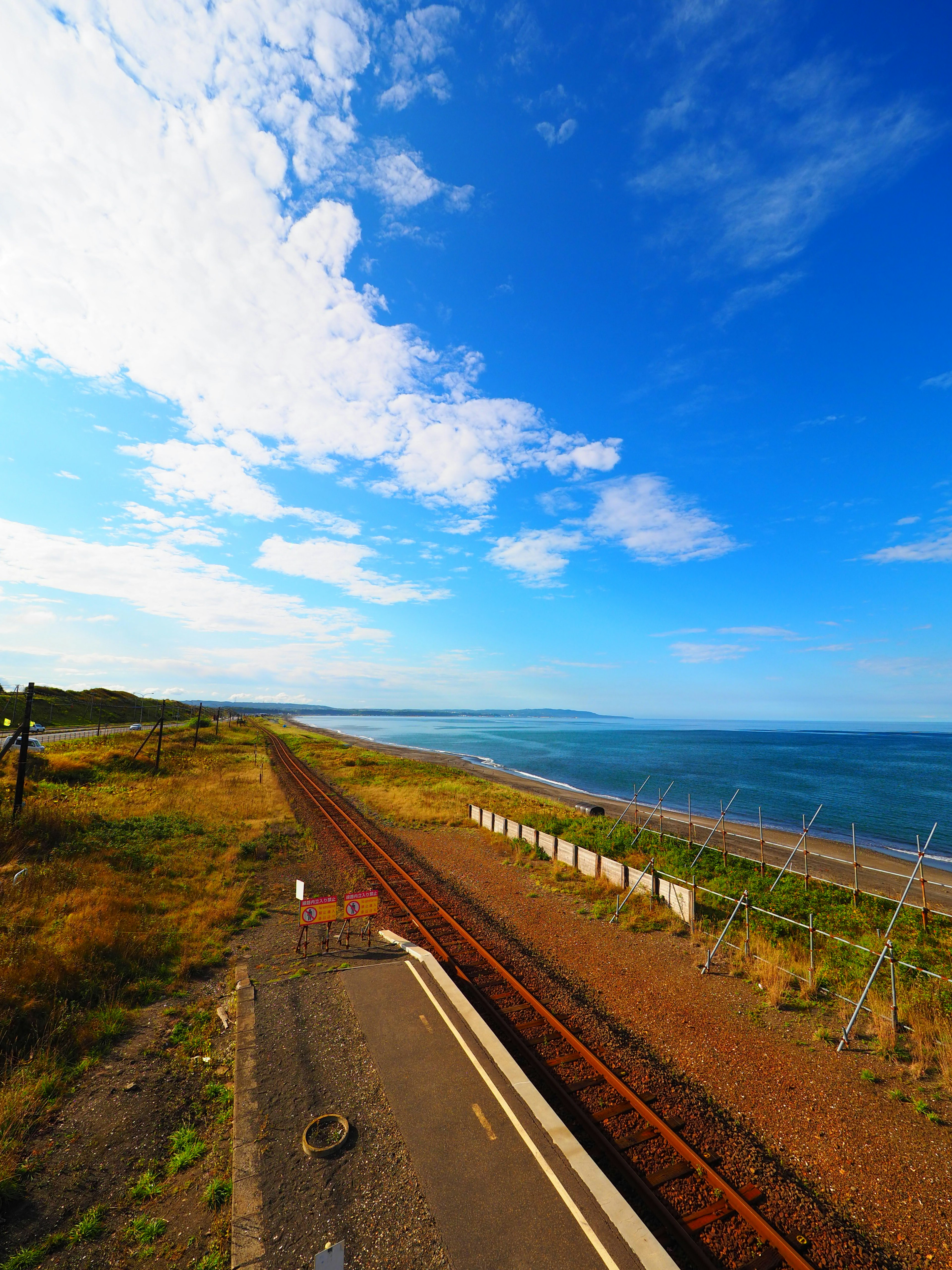 ทิวทัศน์ของทางรถไฟข้างชายฝั่งท้องฟ้าสีฟ้าและเมฆสีขาว