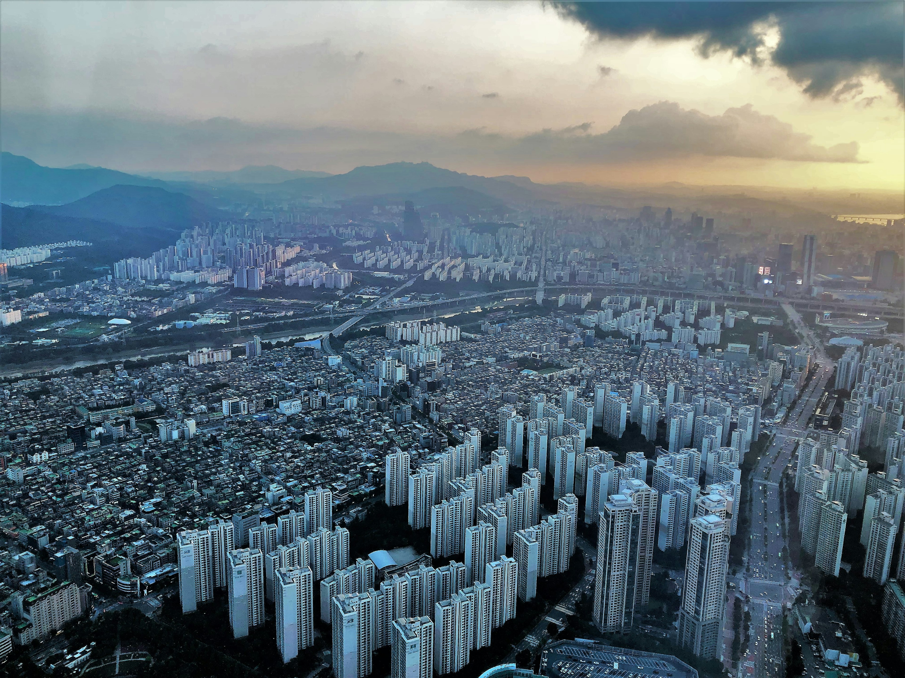 Vista aérea de edificios altos urbanos con montañas al fondo durante el atardecer