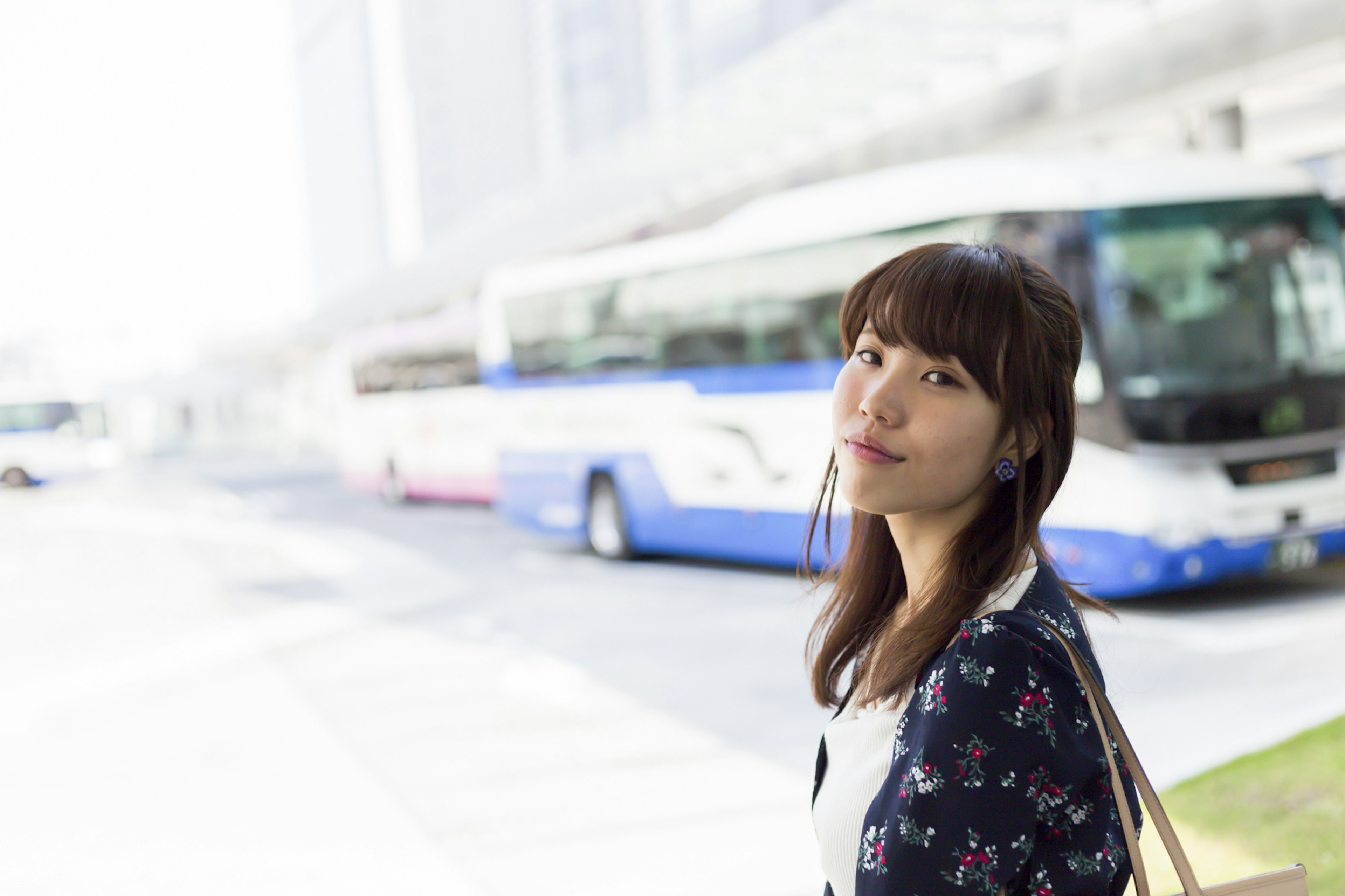 Portrait d'une femme souriante à un arrêt de bus avec des bus en arrière-plan