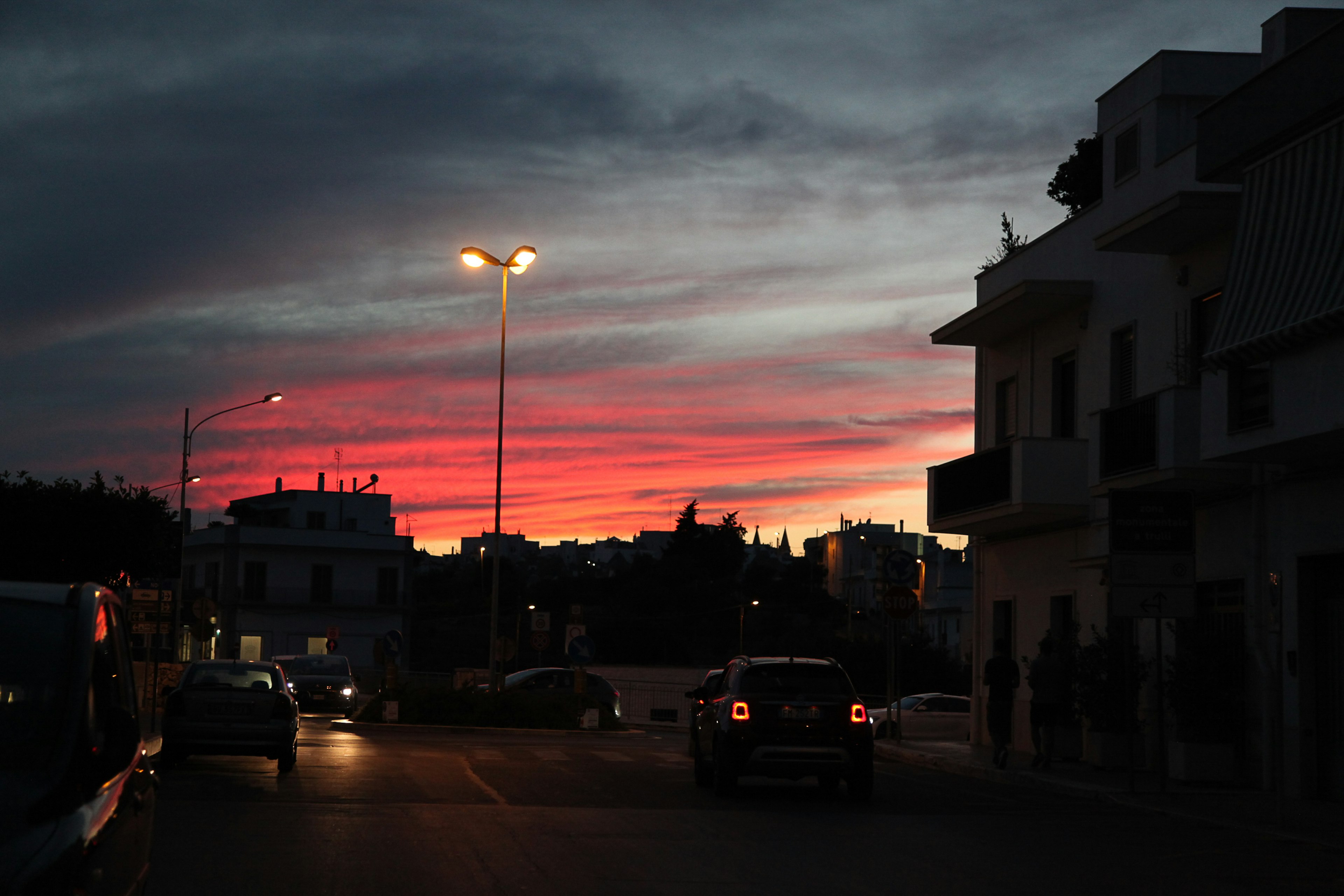 Bunter Sonnenuntergangshimmel mit Silhouetten von Gebäuden und Autos