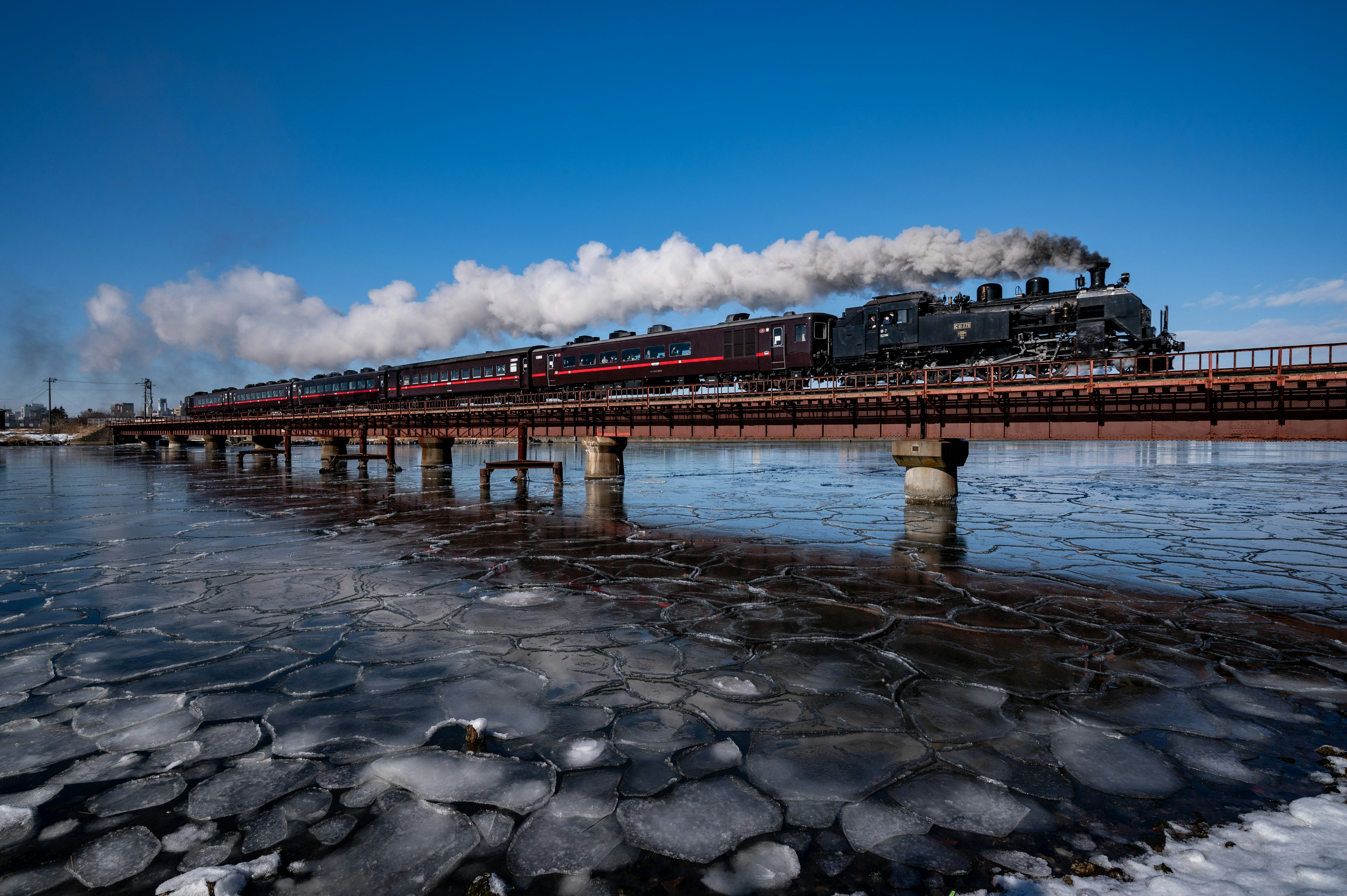 Locomotora de vapor cruzando un puente sobre agua helada