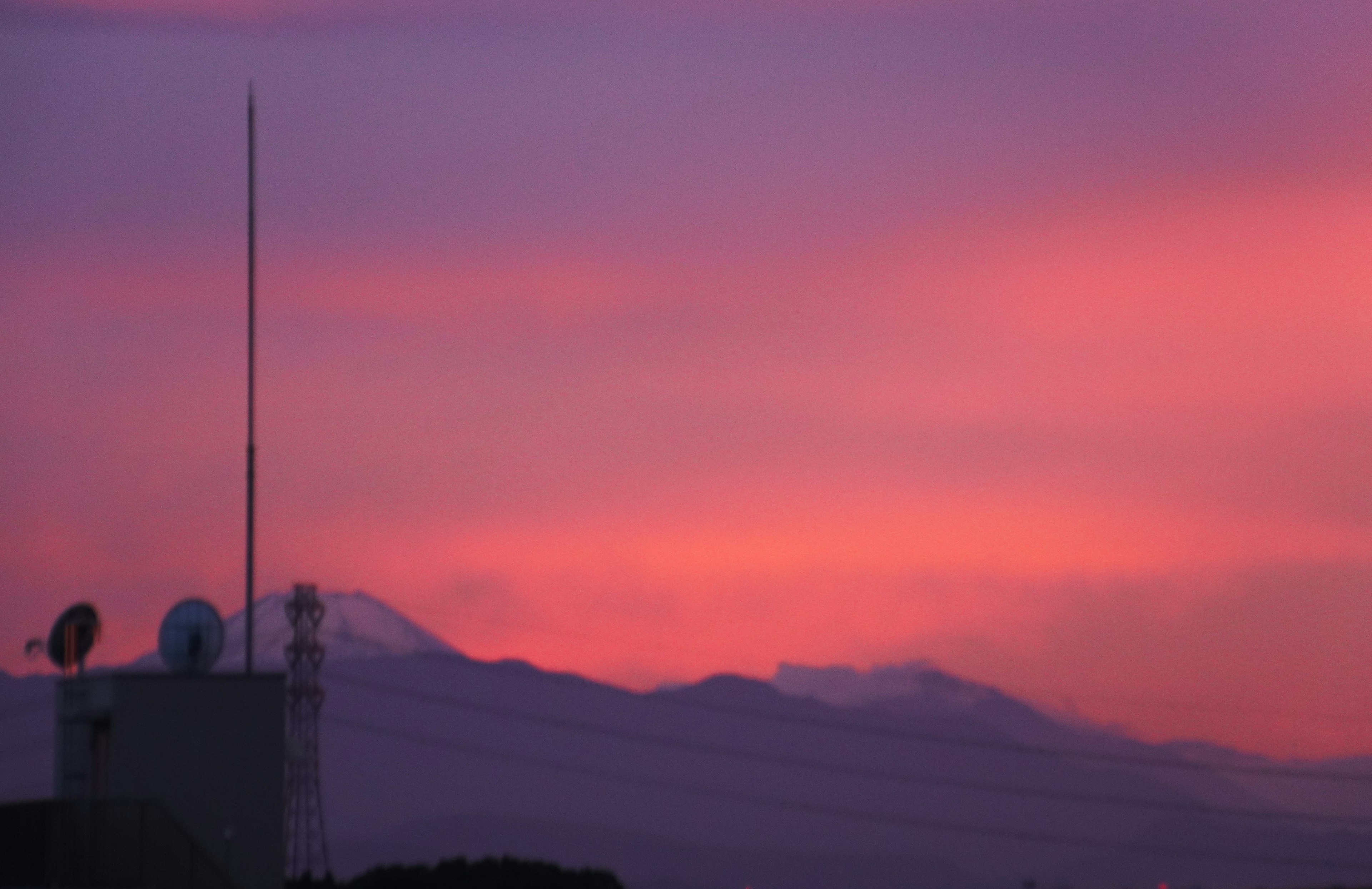 Silueta de un edificio contra un cielo de atardecer con montañas