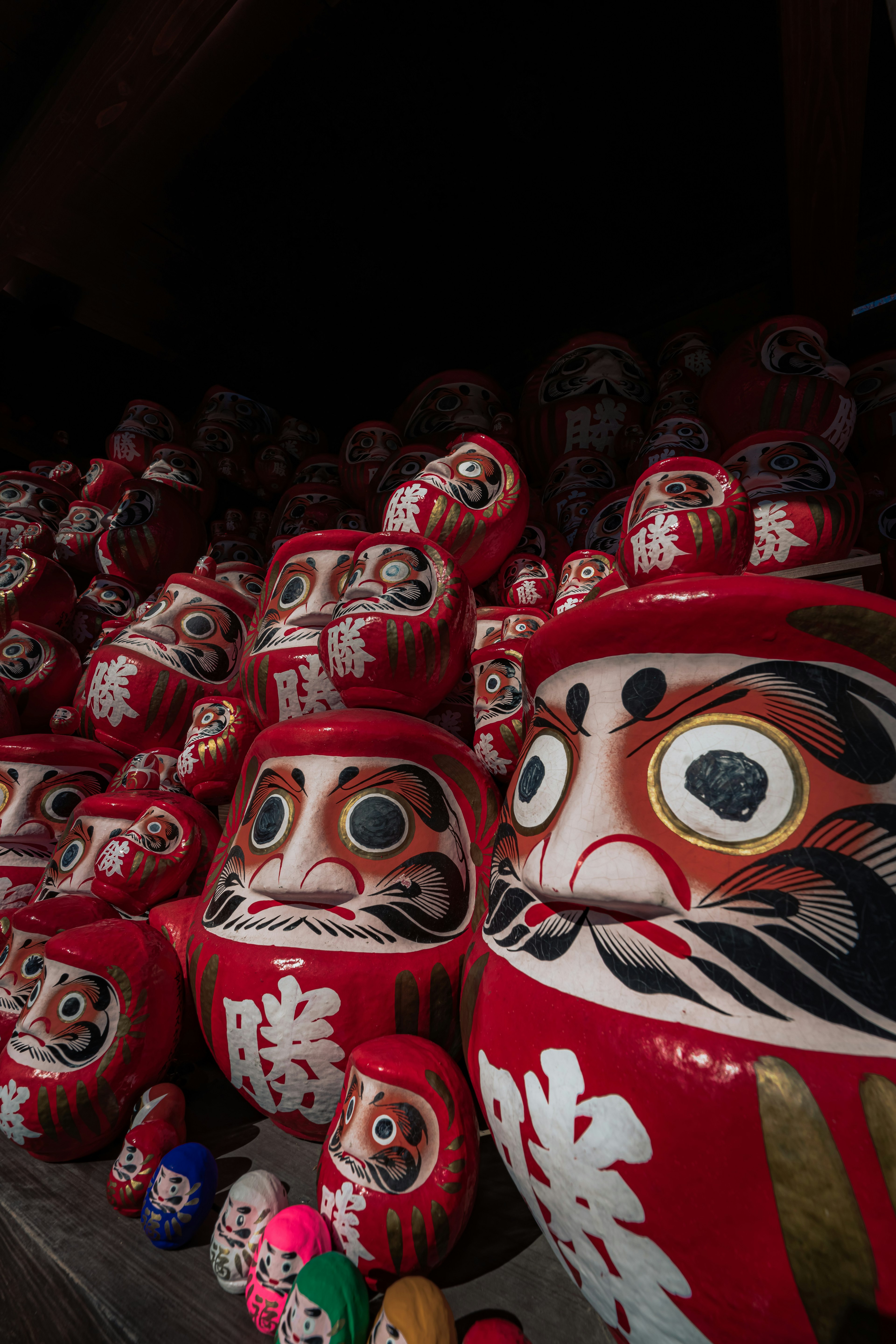 Eine Sammlung roter Daruma-Puppen, die zusammen ausgestellt sind