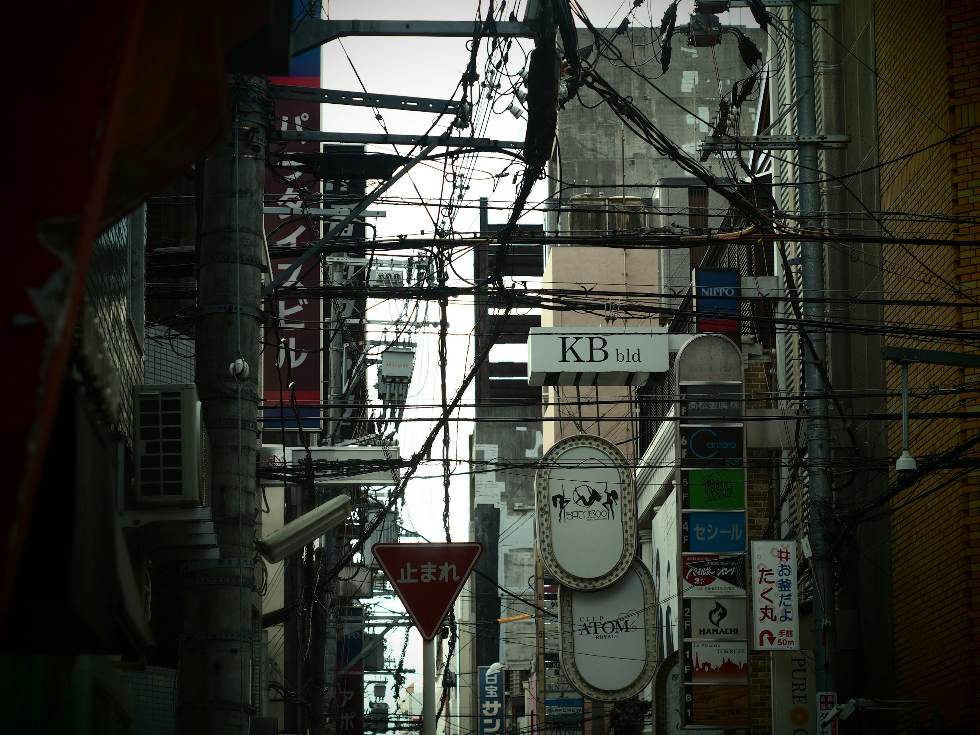 Narrow street with various signs and overhead power lines