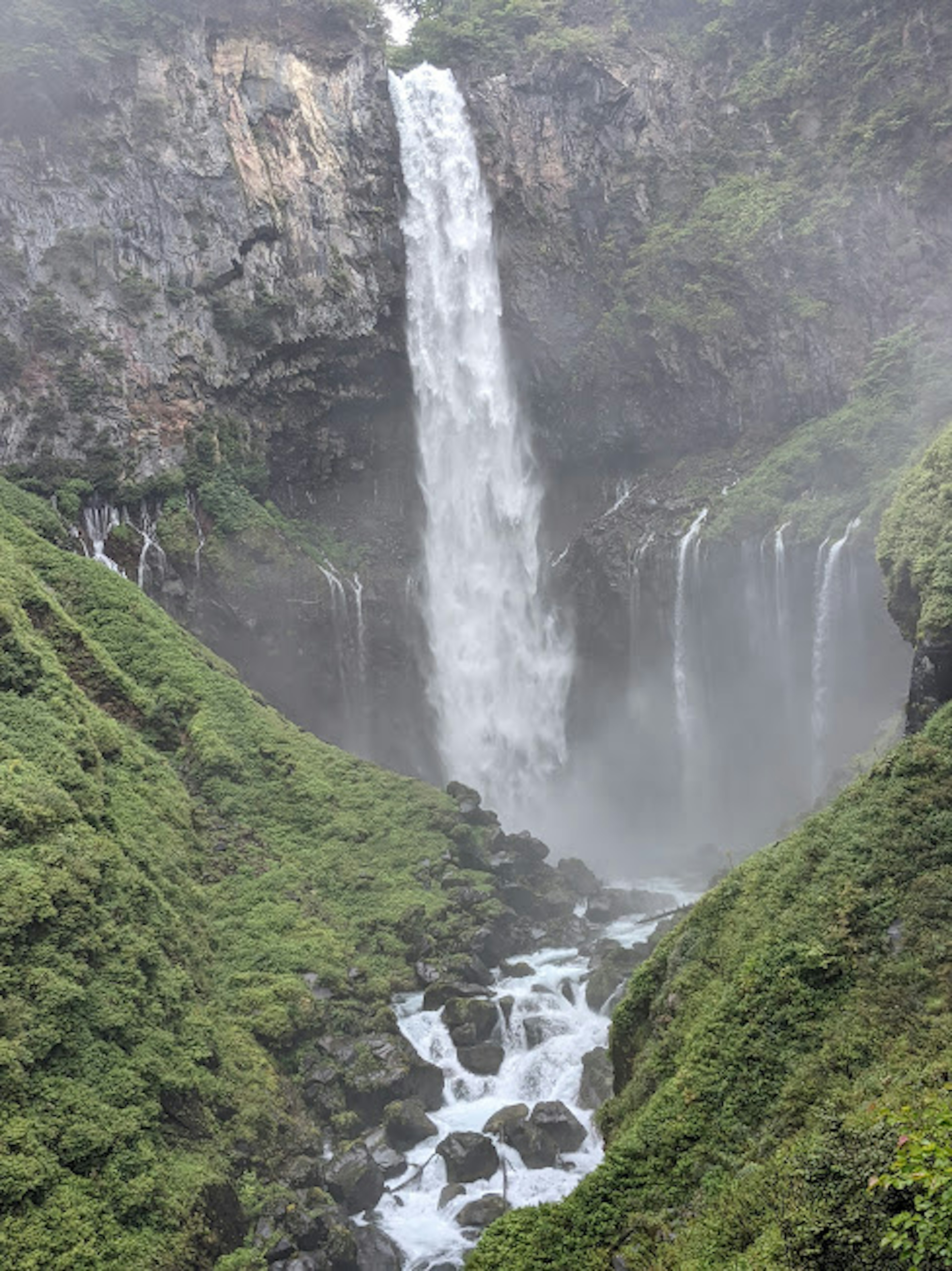 Sebuah air terjun yang mengalir dikelilingi oleh vegetasi yang subur