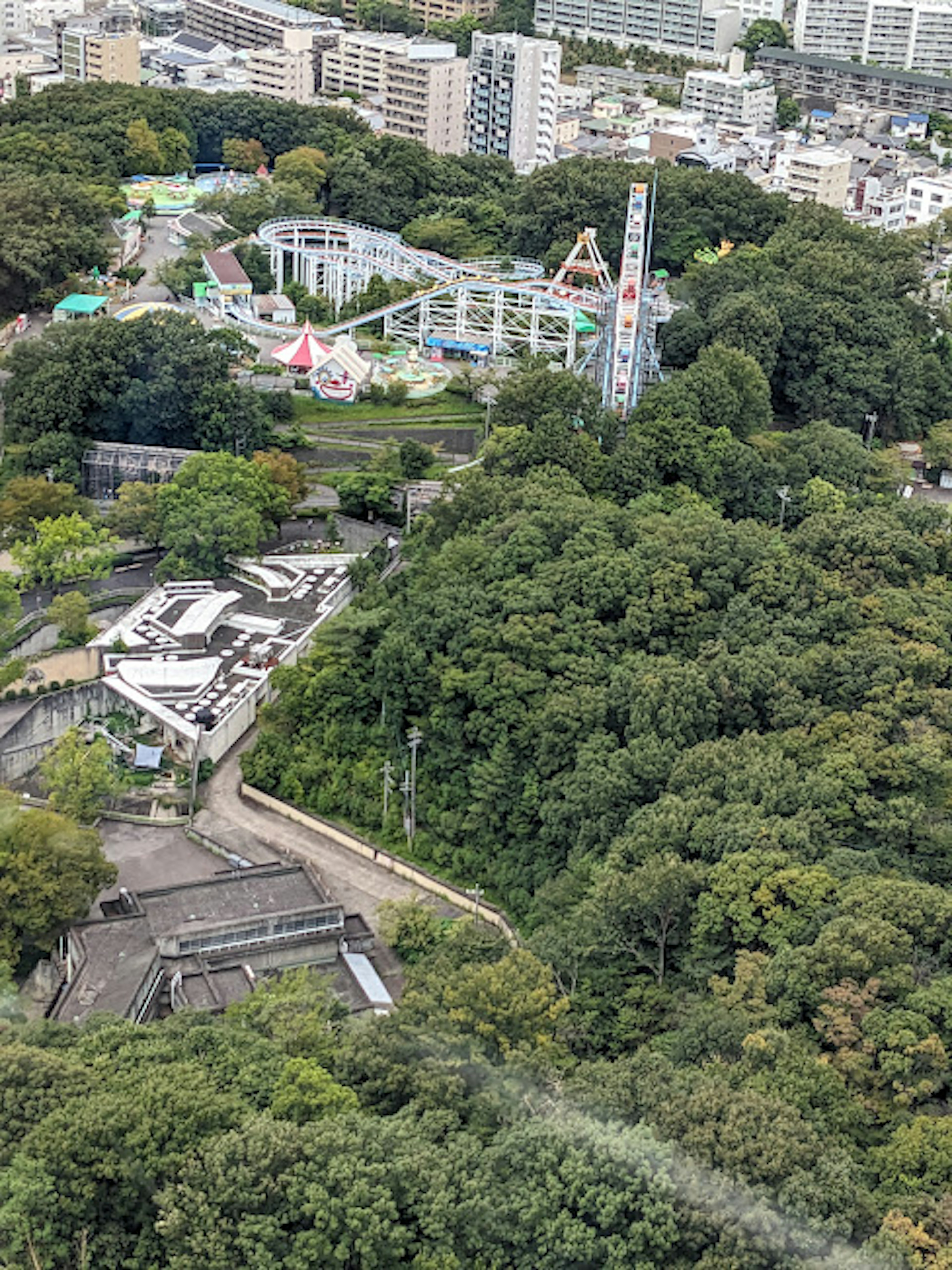 Vue aérienne d'un parc et d'une zone d'attractions entourés de verdure avec des manèges et des structures