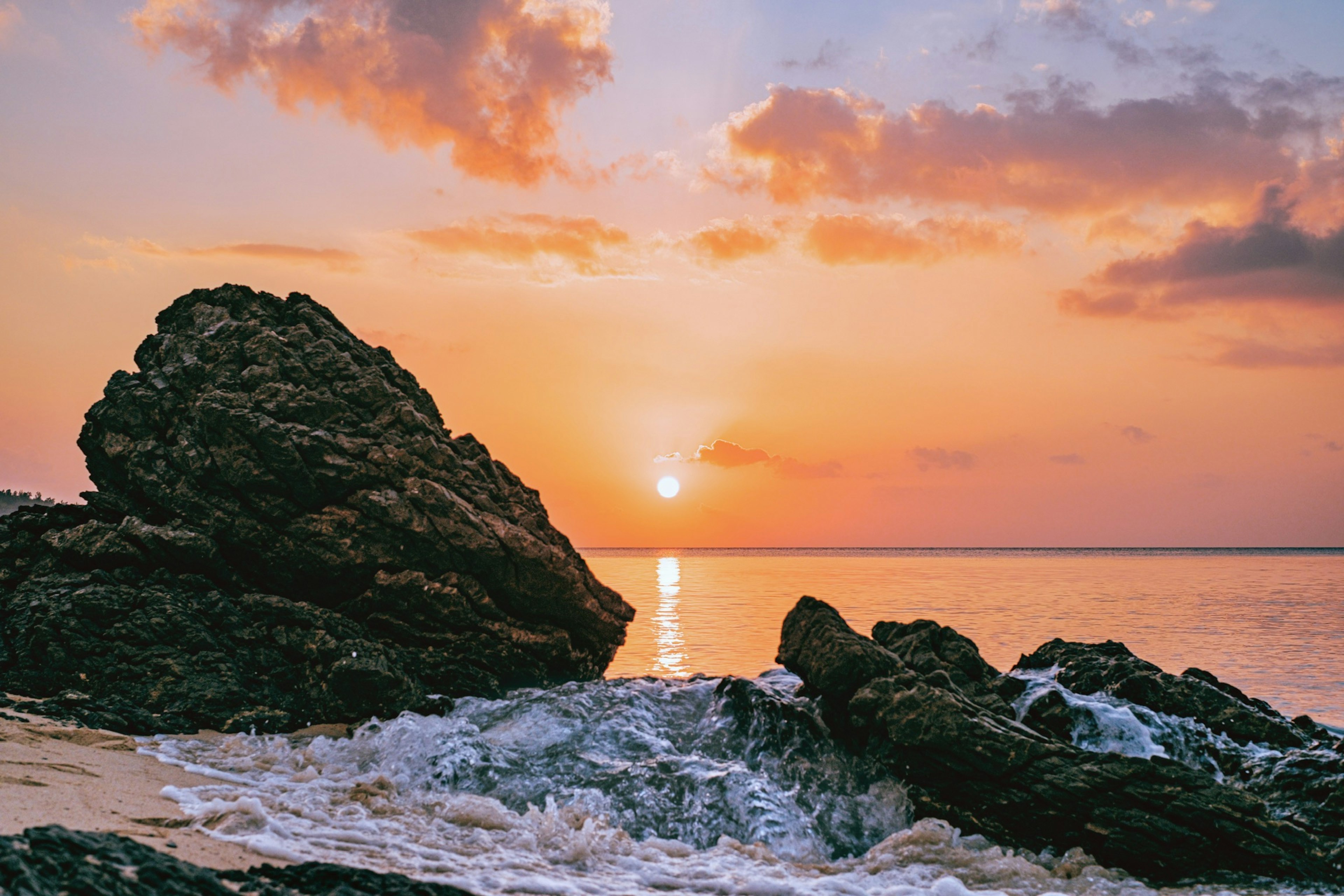 Schöne Landschaft des Sonnenuntergangs über dem Ozean mit sichtbaren Felsen und Wellen