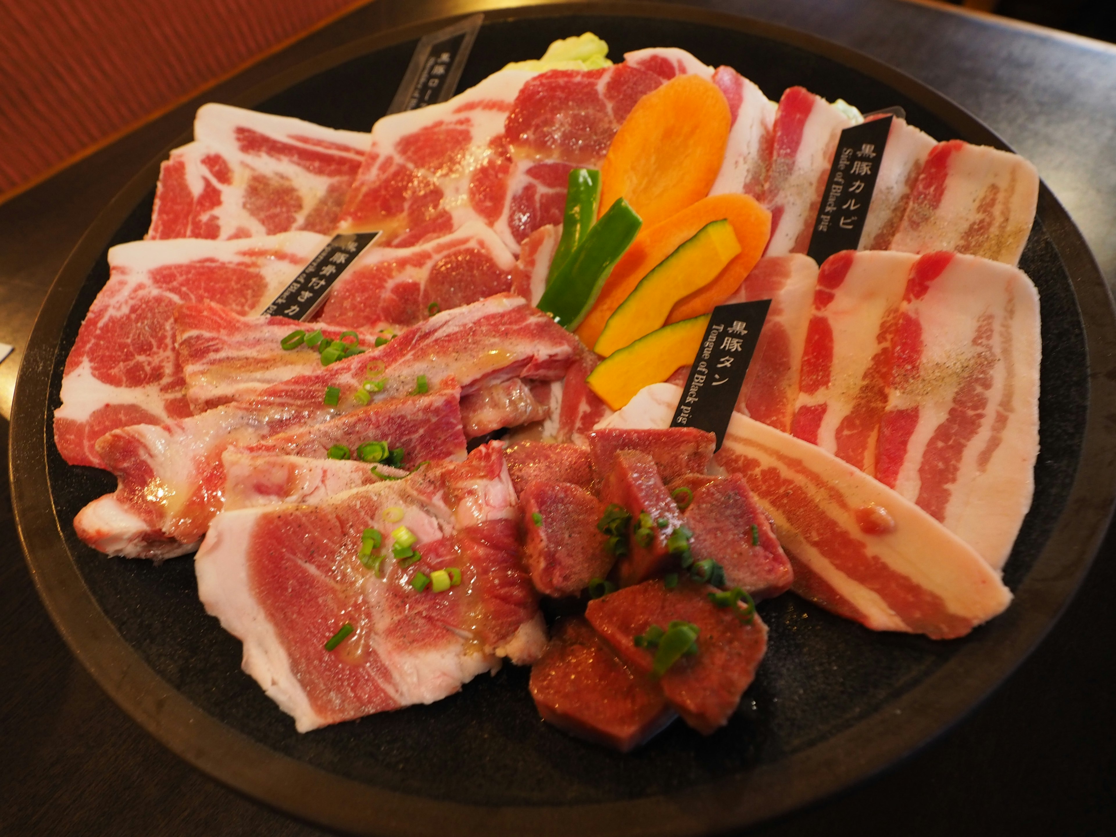 A colorful assortment of meats beautifully arranged on a black platter