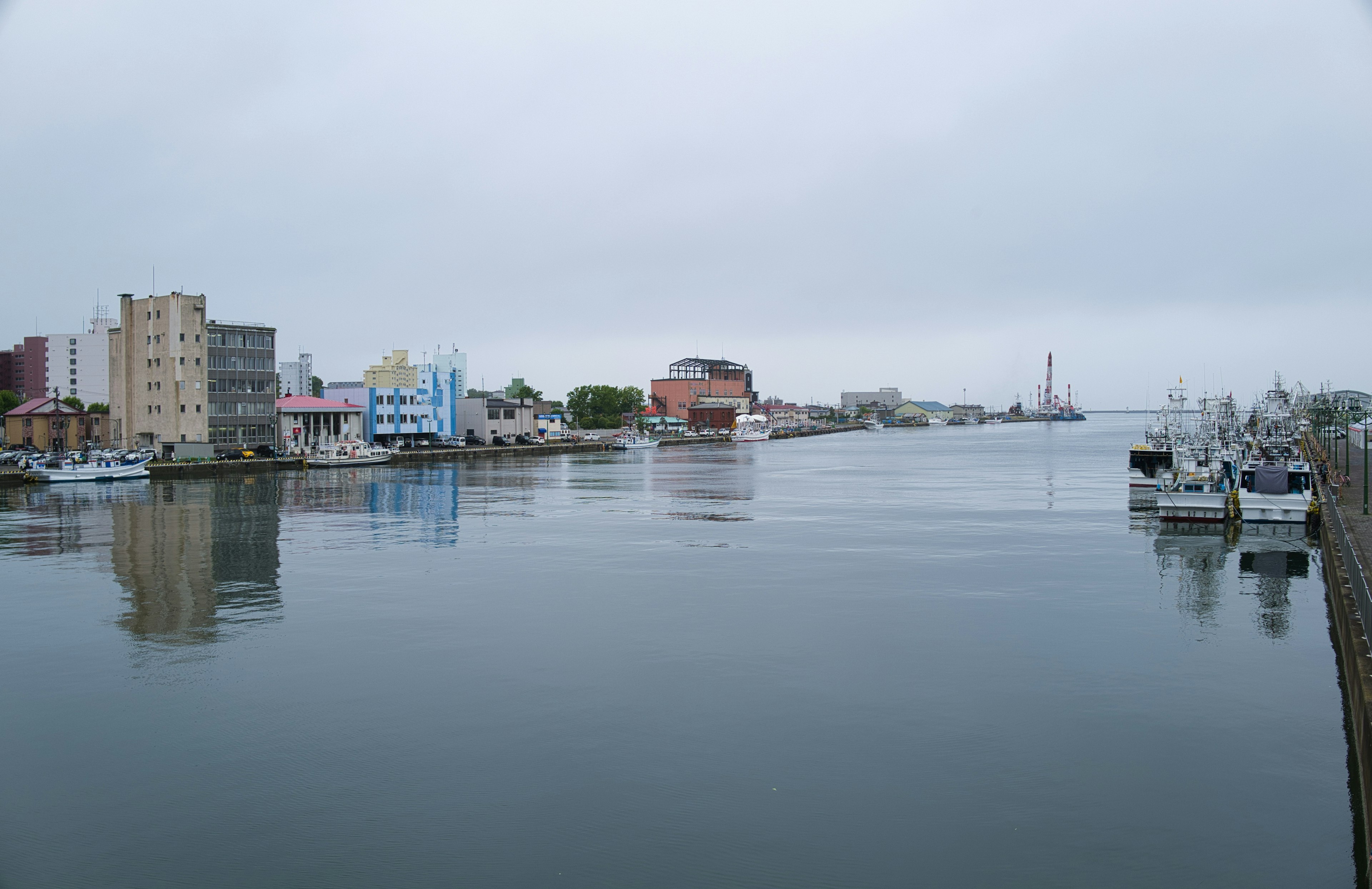 Pemandangan pelabuhan yang tenang dengan pantulan bangunan dan perahu