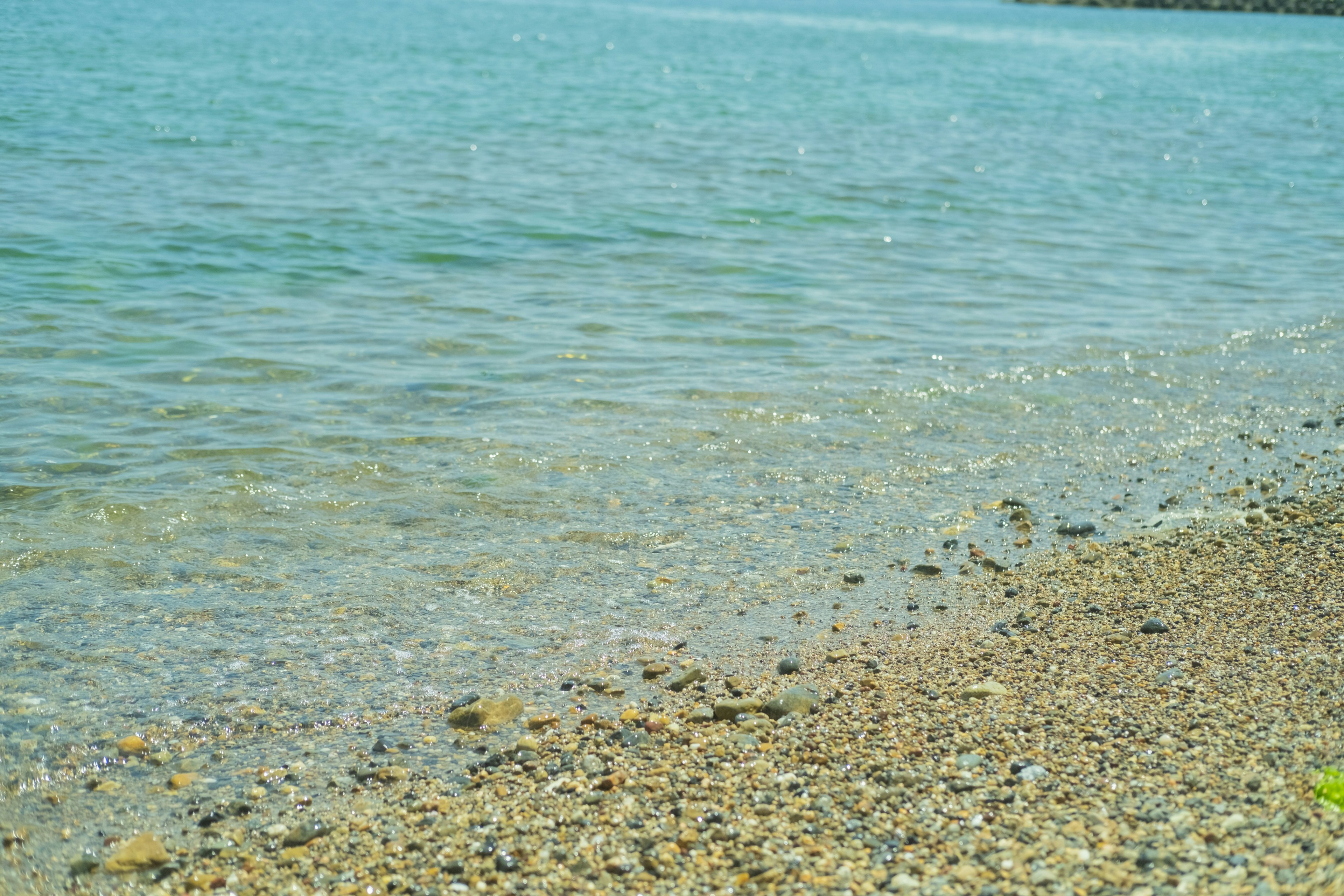 Pemandangan pantai dengan air jernih dan kerikil