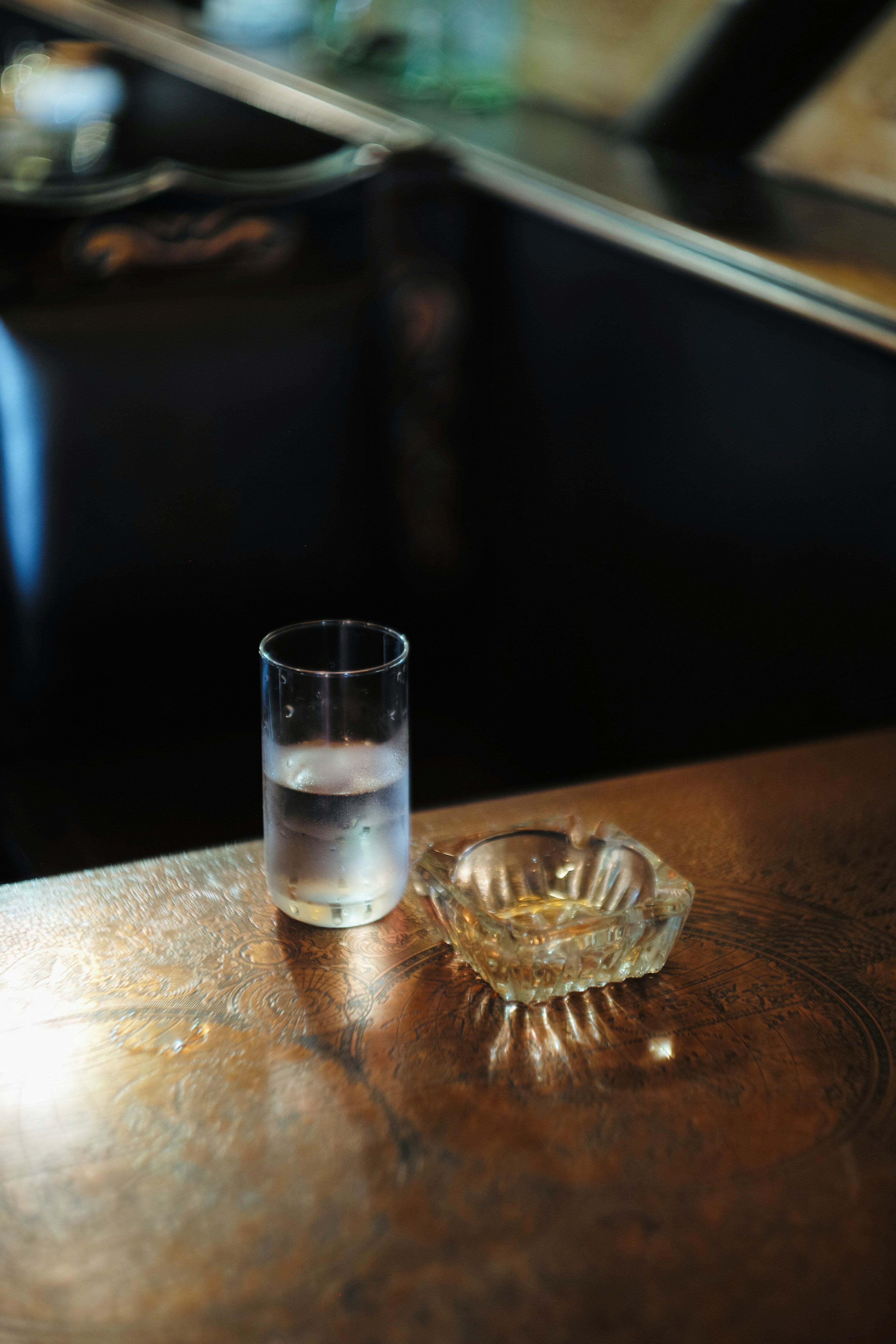 Un vaso de agua clara y un cenicero sobre una mesa de madera