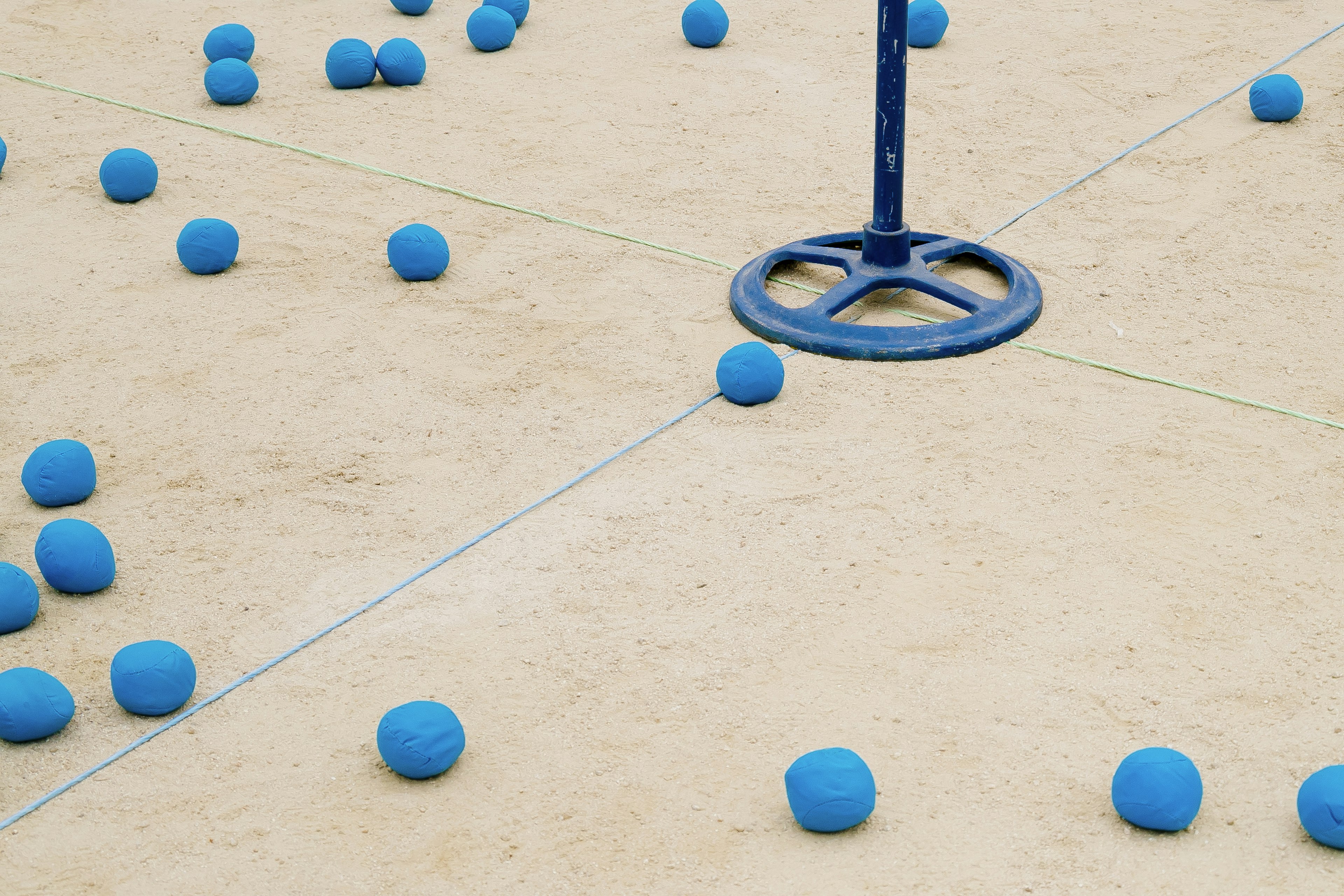 Blue balls scattered on sandy ground with a blue stand