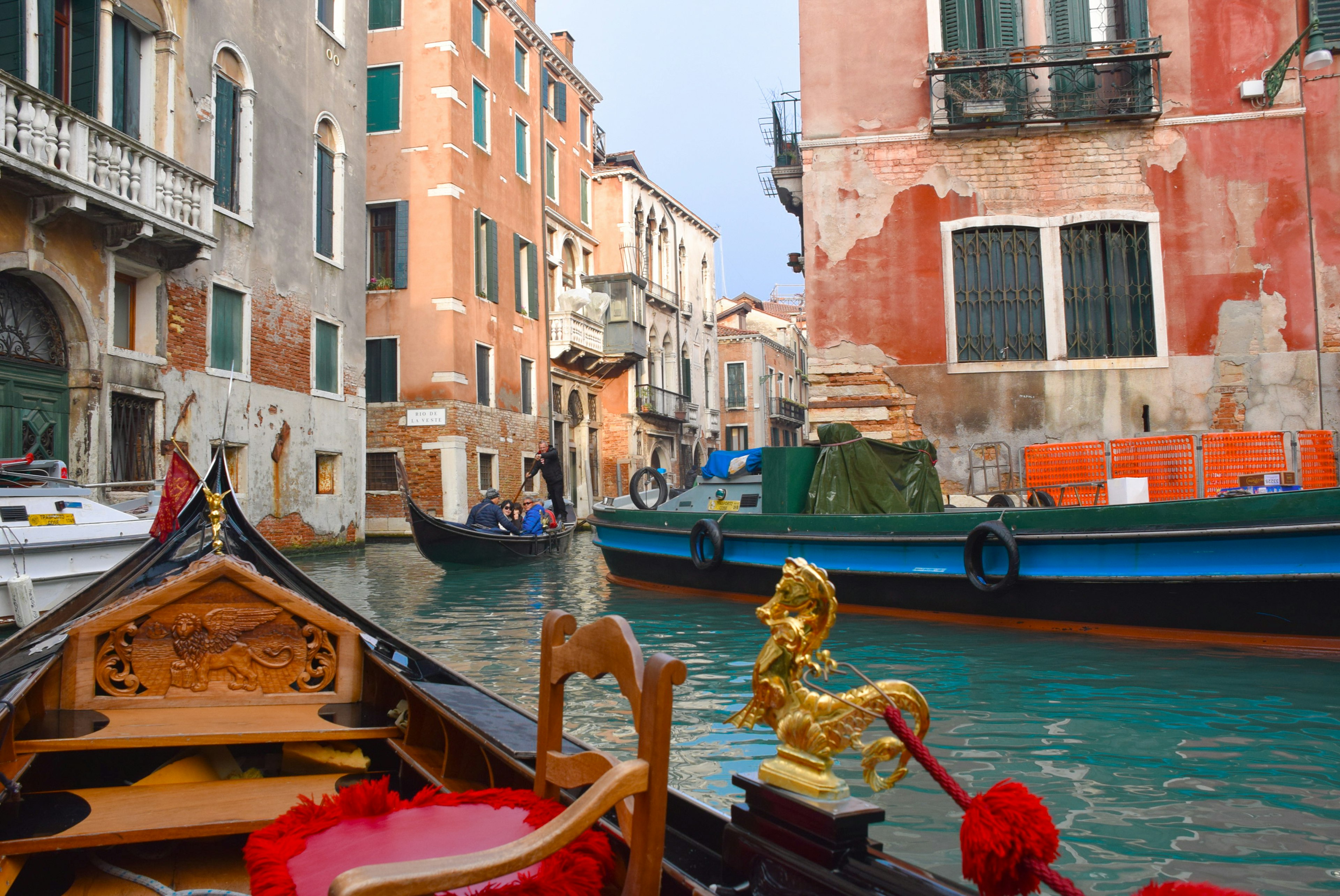 Pemandangan kanal Venesia dari gondola dengan bangunan berwarna-warni dan perahu