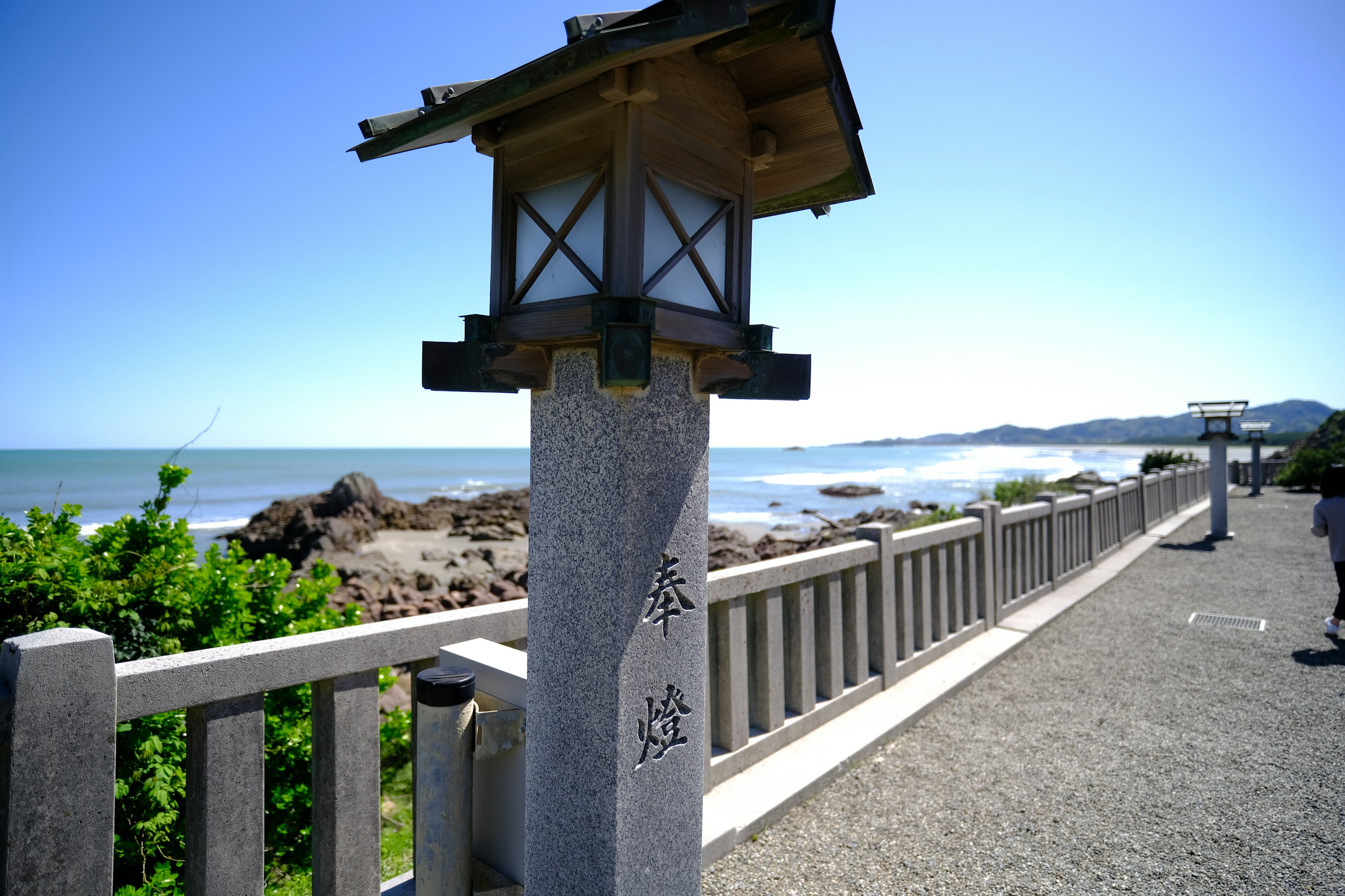 海岸沿いの石灯籠と柵の風景晴れた青空