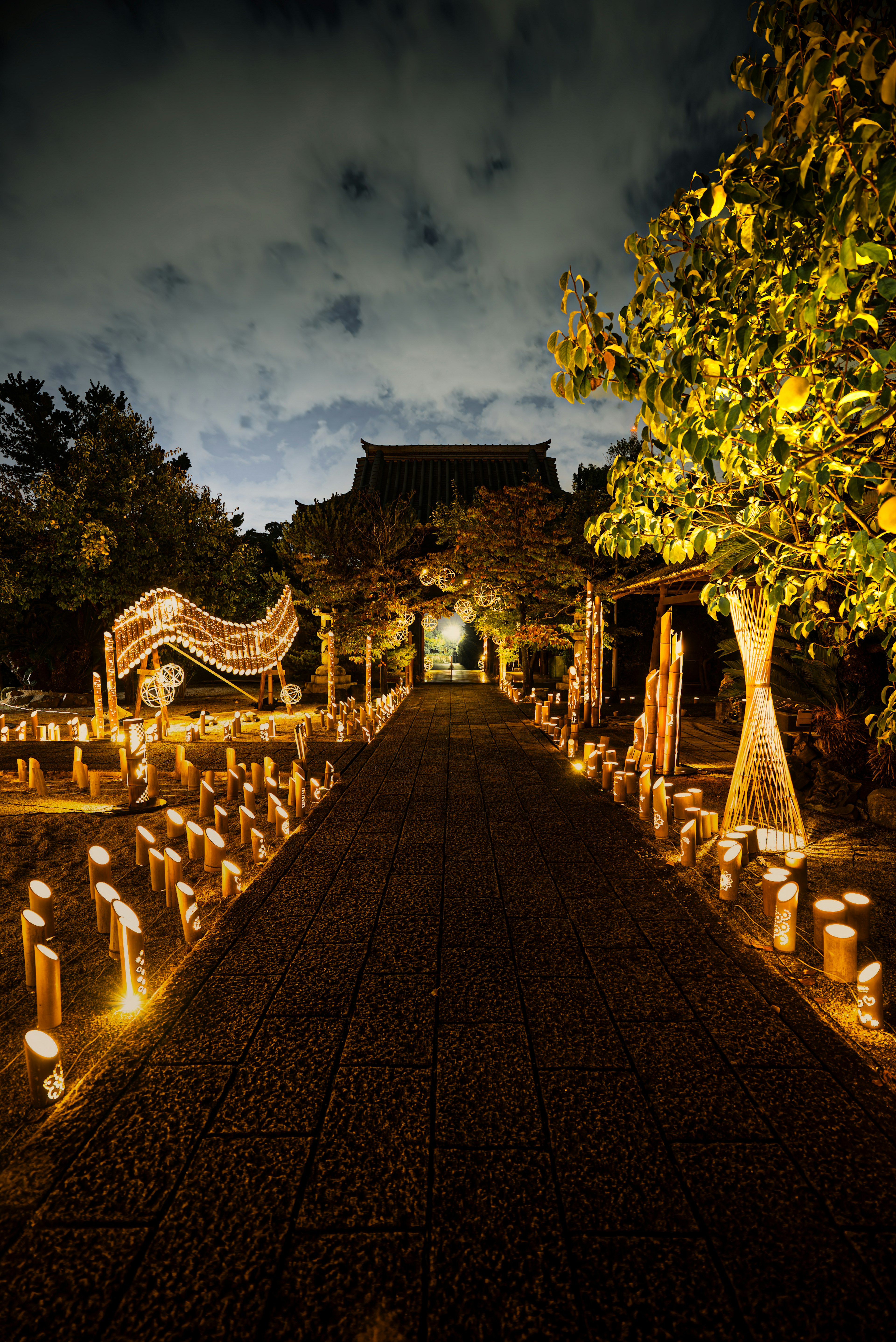 Weg, der von sanften Lichtern in einem Garten mit Bäumen beleuchtet wird