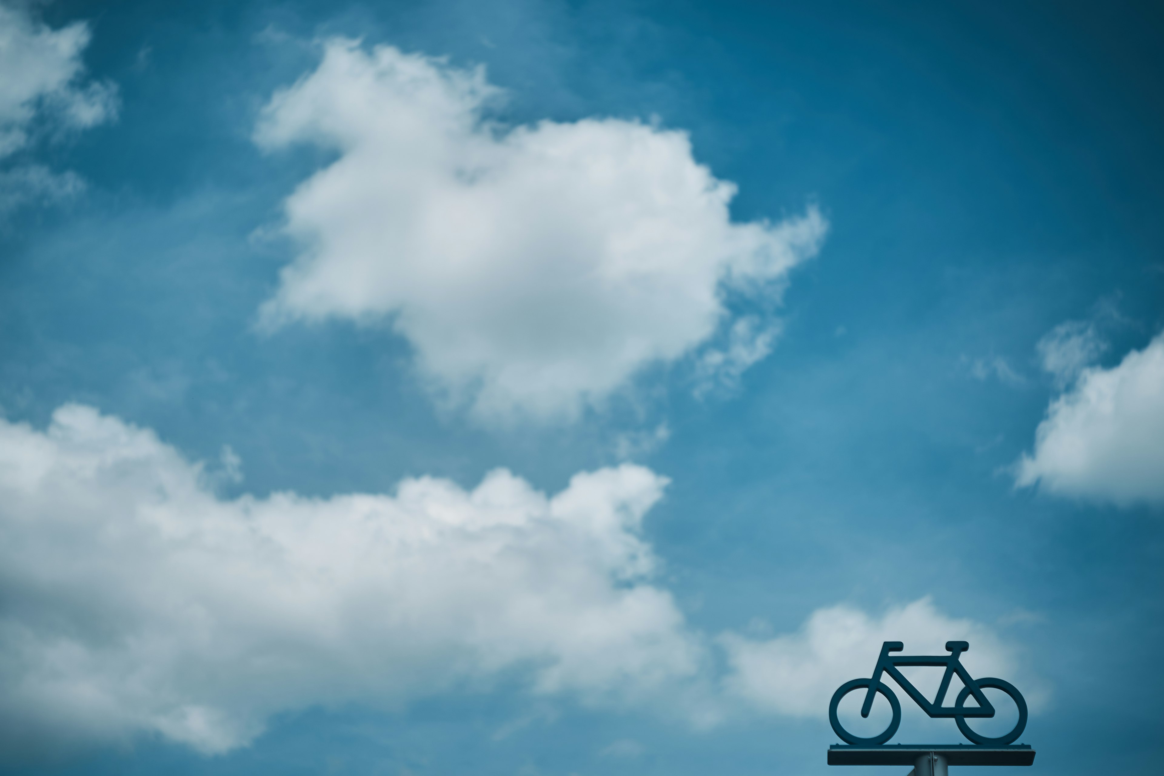 青空に浮かぶ自転車のシルエットと白い雲