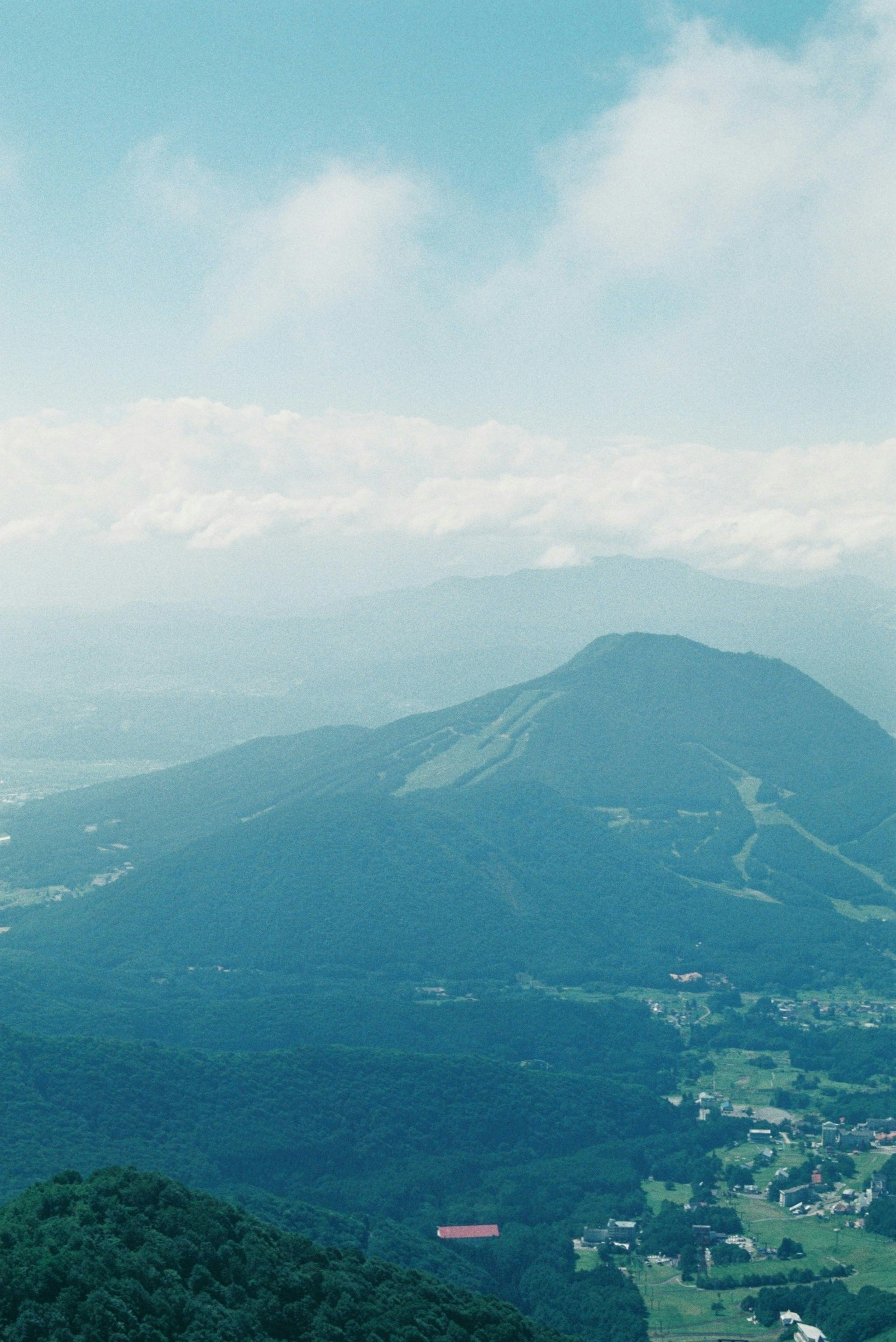 青い空と雲に囲まれた山の風景 緑の山と谷が広がる